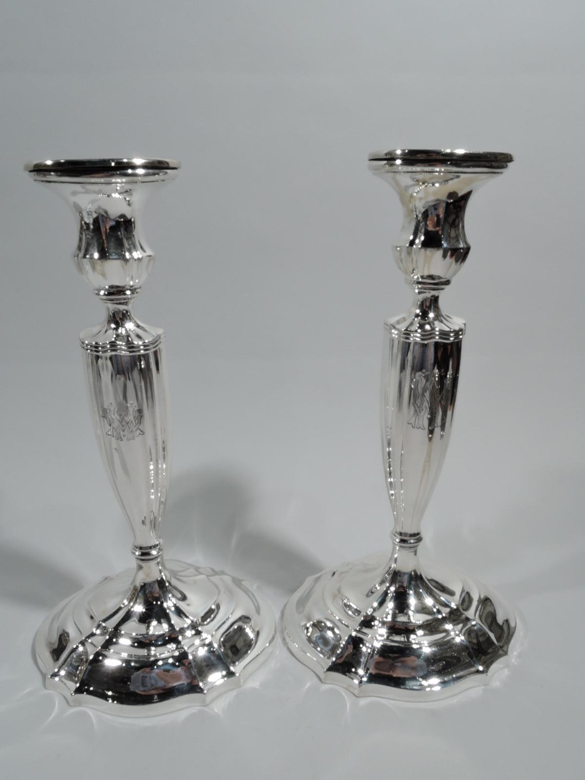 Pair of Edwardian sterling silver candlesticks. Made by Gorham in Providence in 1905. Each: Ovoid, tapering, and fluted shaft with interlaced script monogram; stepped oval foot. Urn socket with detachable bobeche. Fully marked including date symbol