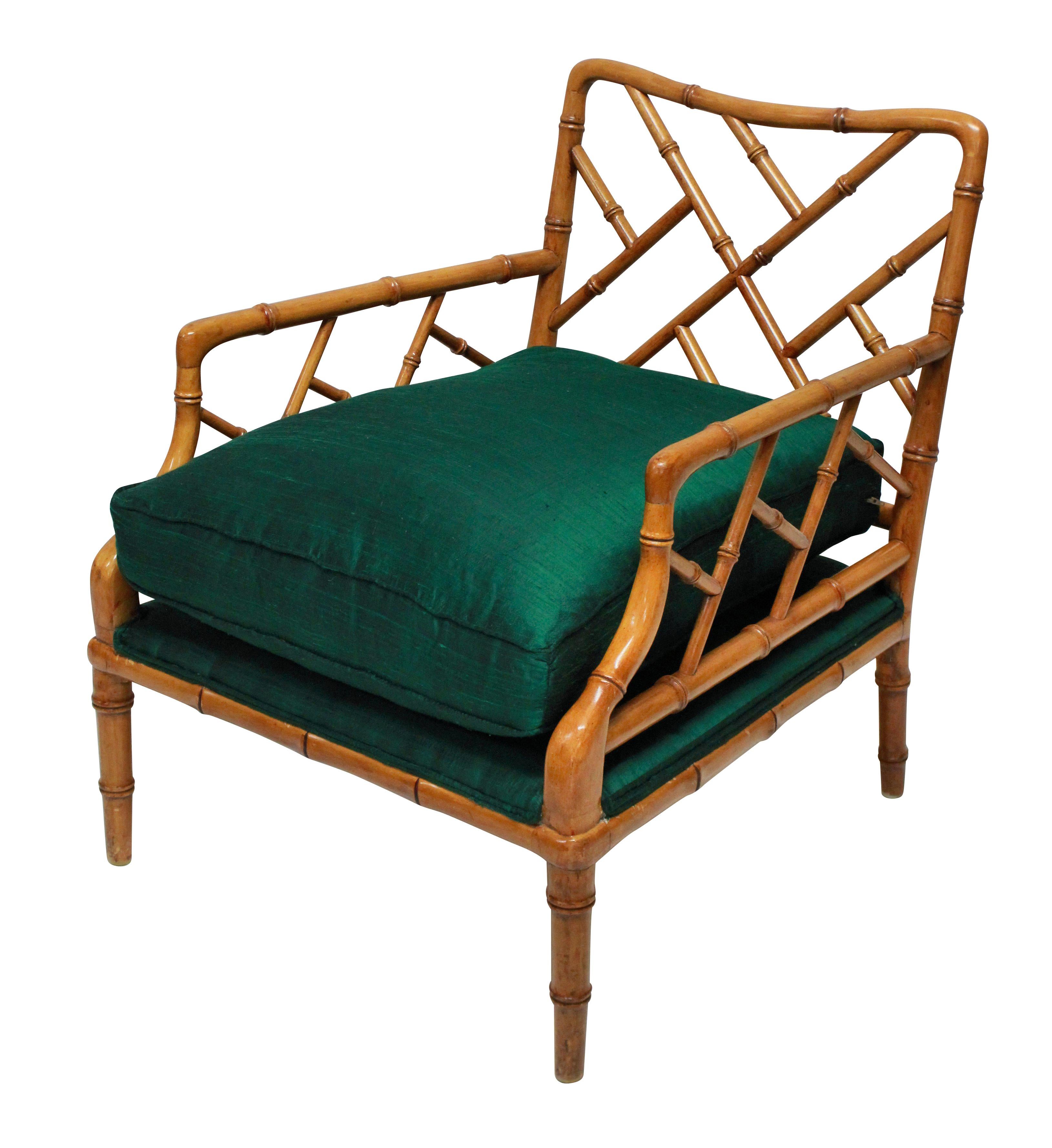 A pair of American faux bamboo cockpen deep armchairs, with newly upholstered emerald green silk seats.

