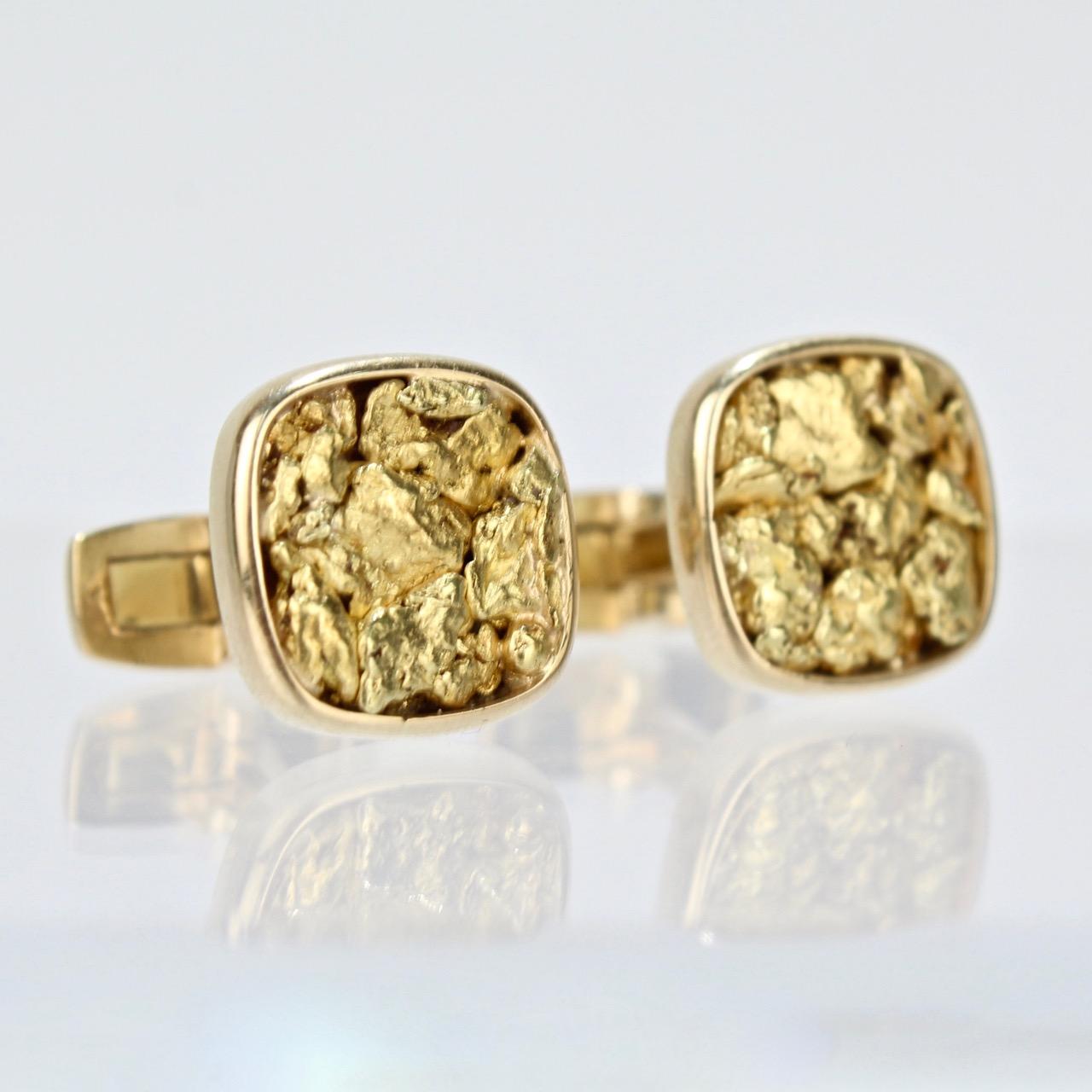 A fine pair of masculine gold nugget cufflinks.

Wonderfully worked with diminutive gold nuggets set in rounded square bezel settings. 

The reverse marked with a leaf maker's mark, a gold miner's tools mark, and 14K.

Width: just over 1/2