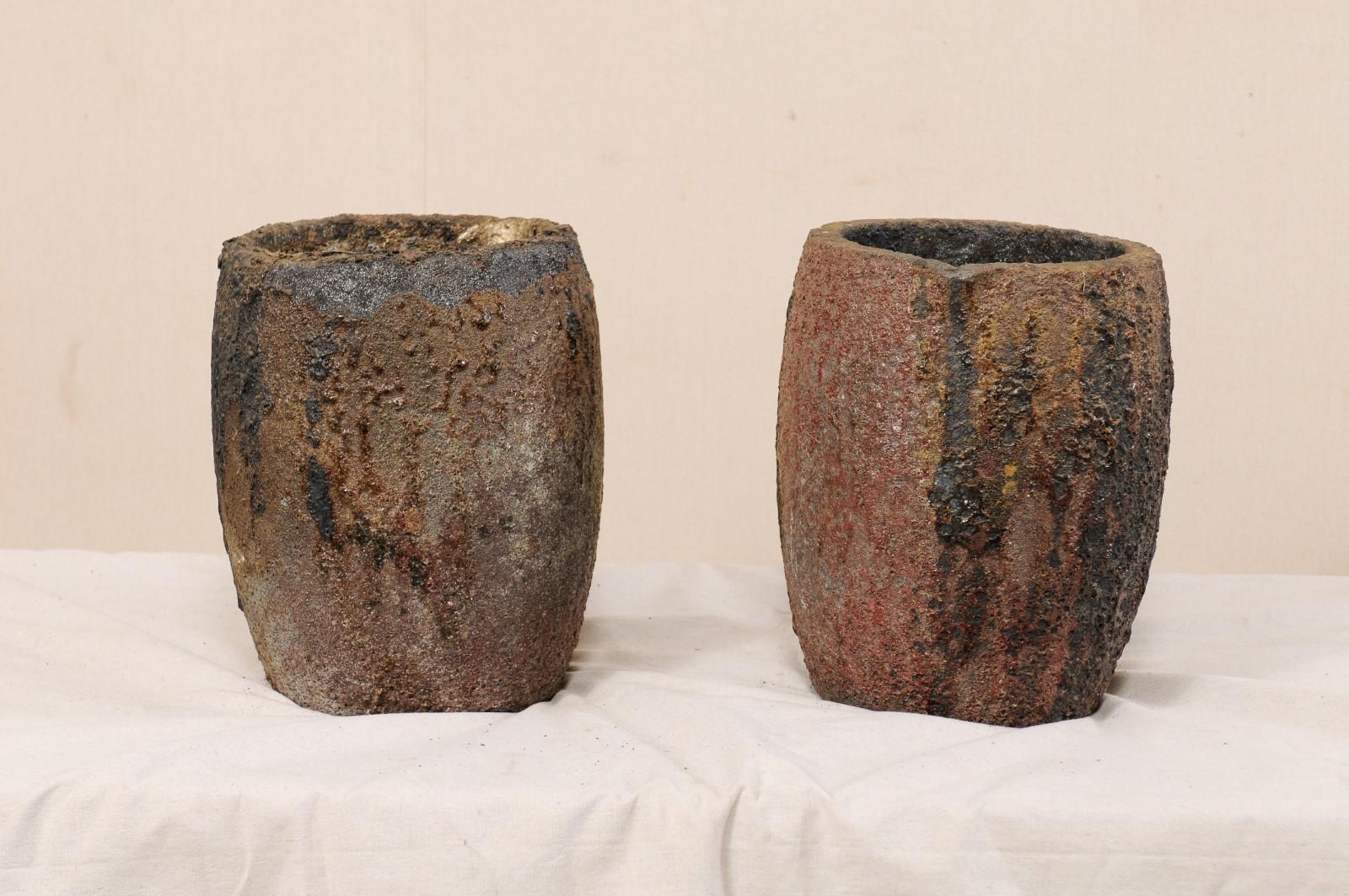 A pair of American industrial cauldrons or melting pots. This pair of vintage foundry pots, once used for extremely high temperature melting, have a wonderful, almost organic appearance with remnants of old materials clinging about the interior and