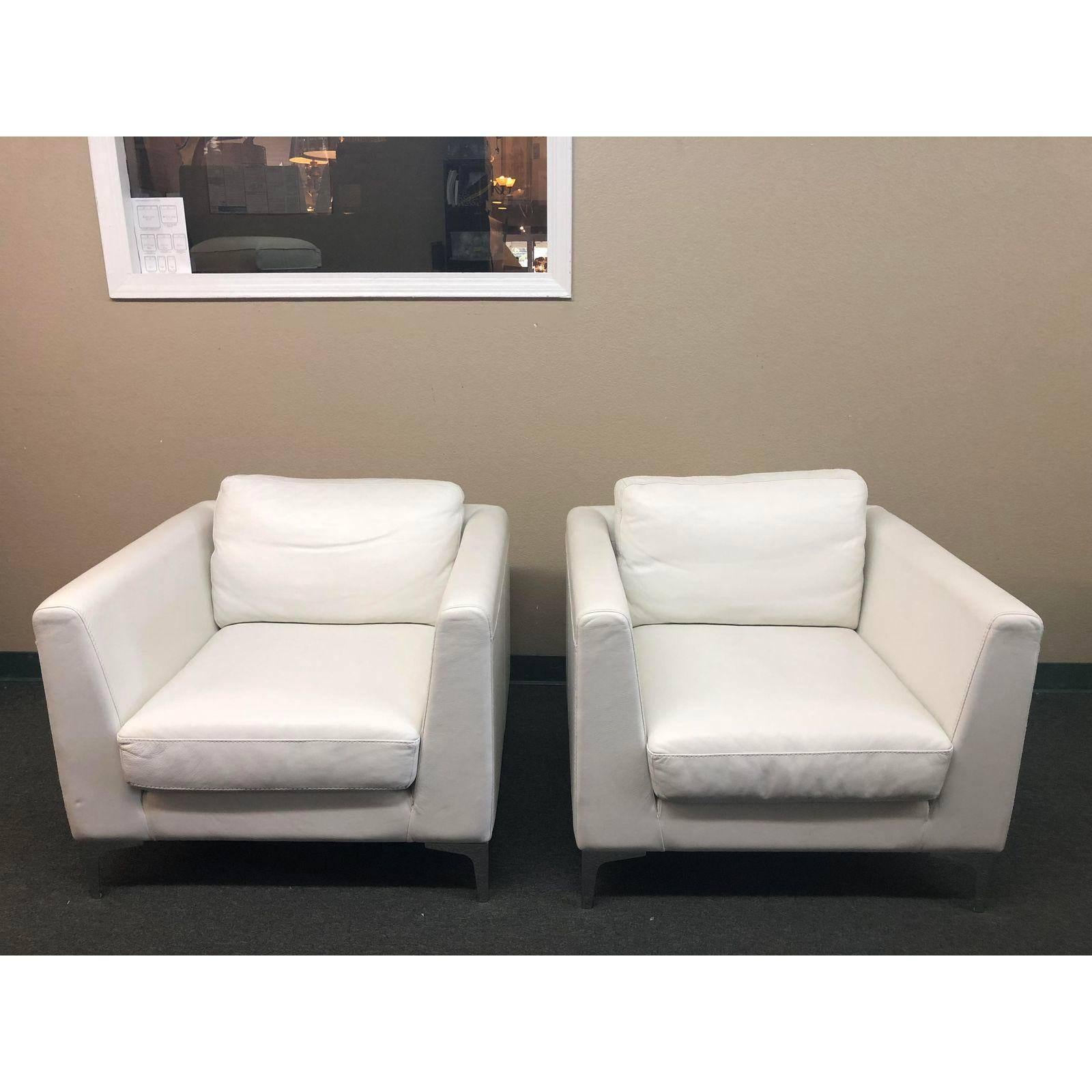 Pair of design within reach Albert arm white leather chairs. Manufactured by American leather for design within reach. The chairs sit on chromed metal legs. They are finished with top stitching detail. Measures: Arms height 26.5 inches, seat height