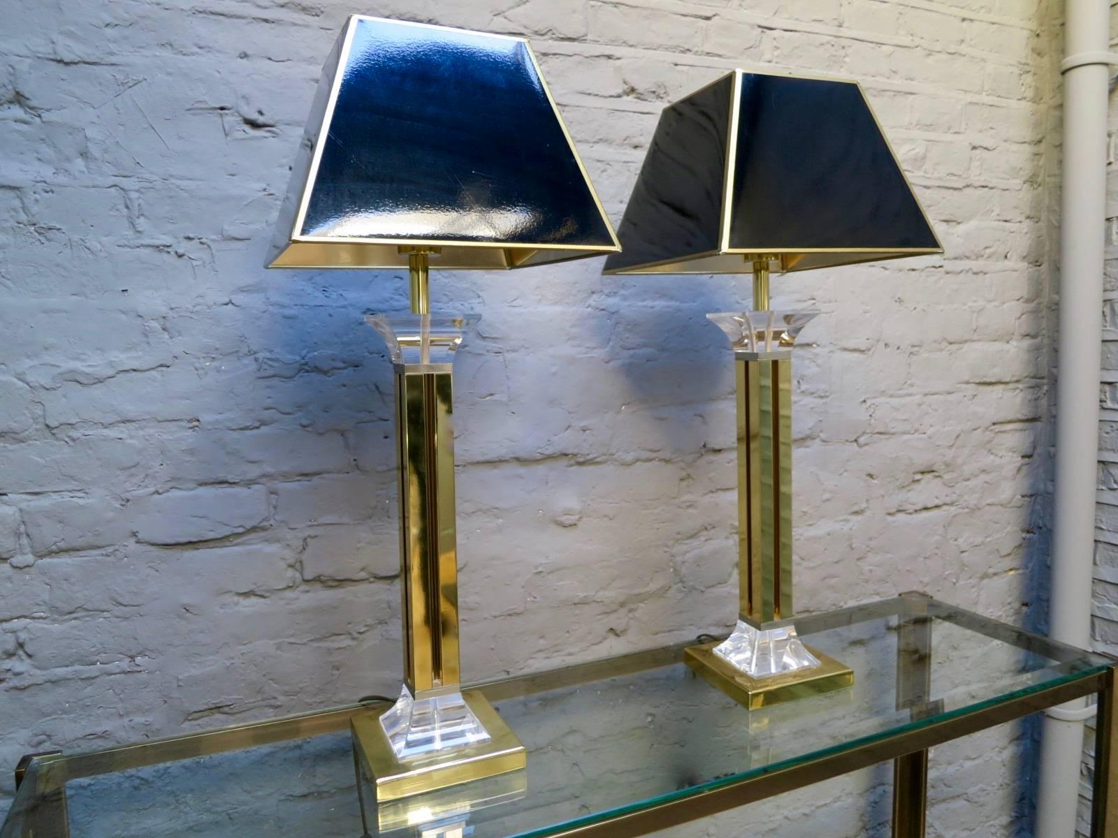 A pair of tall Lucite and gilt brass table lamps with black shades.