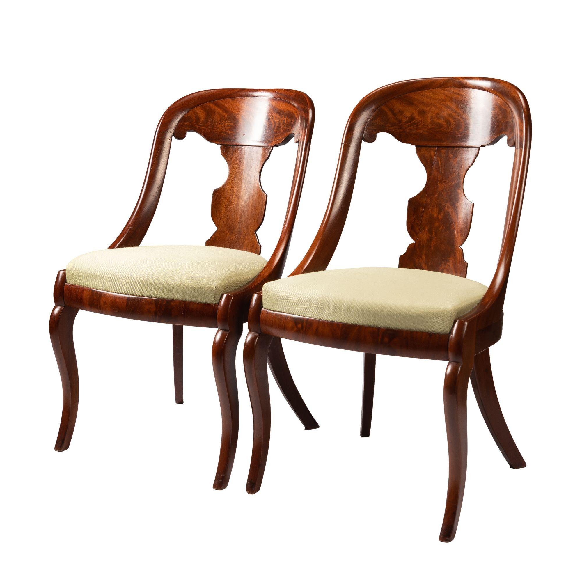 Pair of American mahogany and figured mahogany veneered gondola chairs. The chairs feature a boxed slip seat & single vertical baluster form silhouette back splat below a crest rail. The back is defined by a continuous bull nose molding encompassing