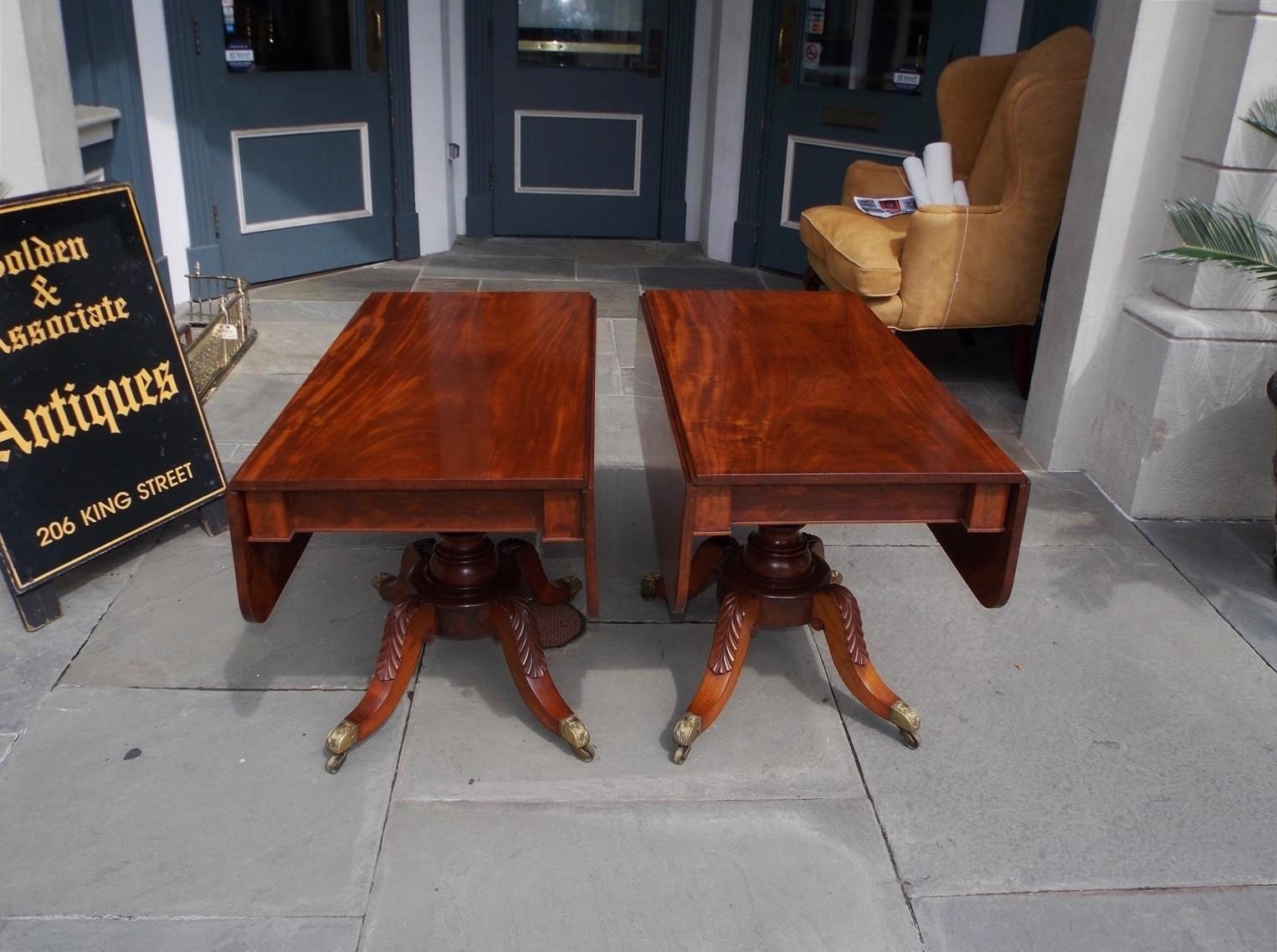 Pair of American mahogany drop-leaf pedestal card tables with turned bulbous centered columns, acanthus carved scroll work saber legs, and terminating on original brass decorative filigree casters. Philadelphia, Early 19th Century.
Tables are