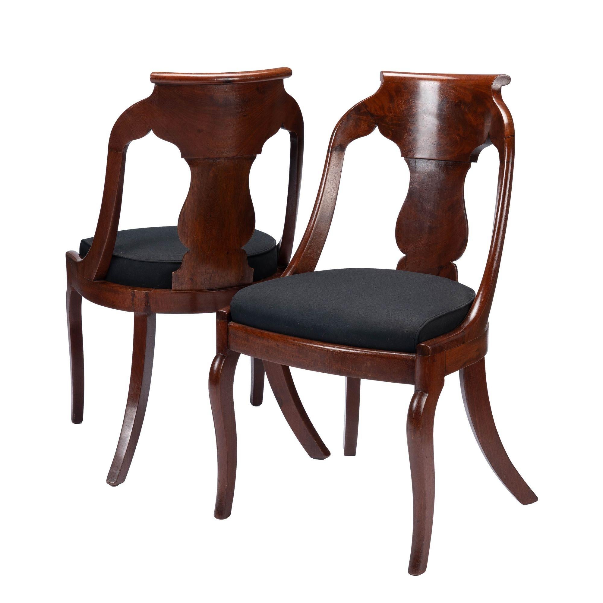 Pair of American neoclassic mahogany and figured mahogany veneered slip seat gondola chairs in the French Restoration taste. The boxed slip seat is fitted to a bowed mahogany front seat frame on pseudo sabre front legs and dramatically raked rear