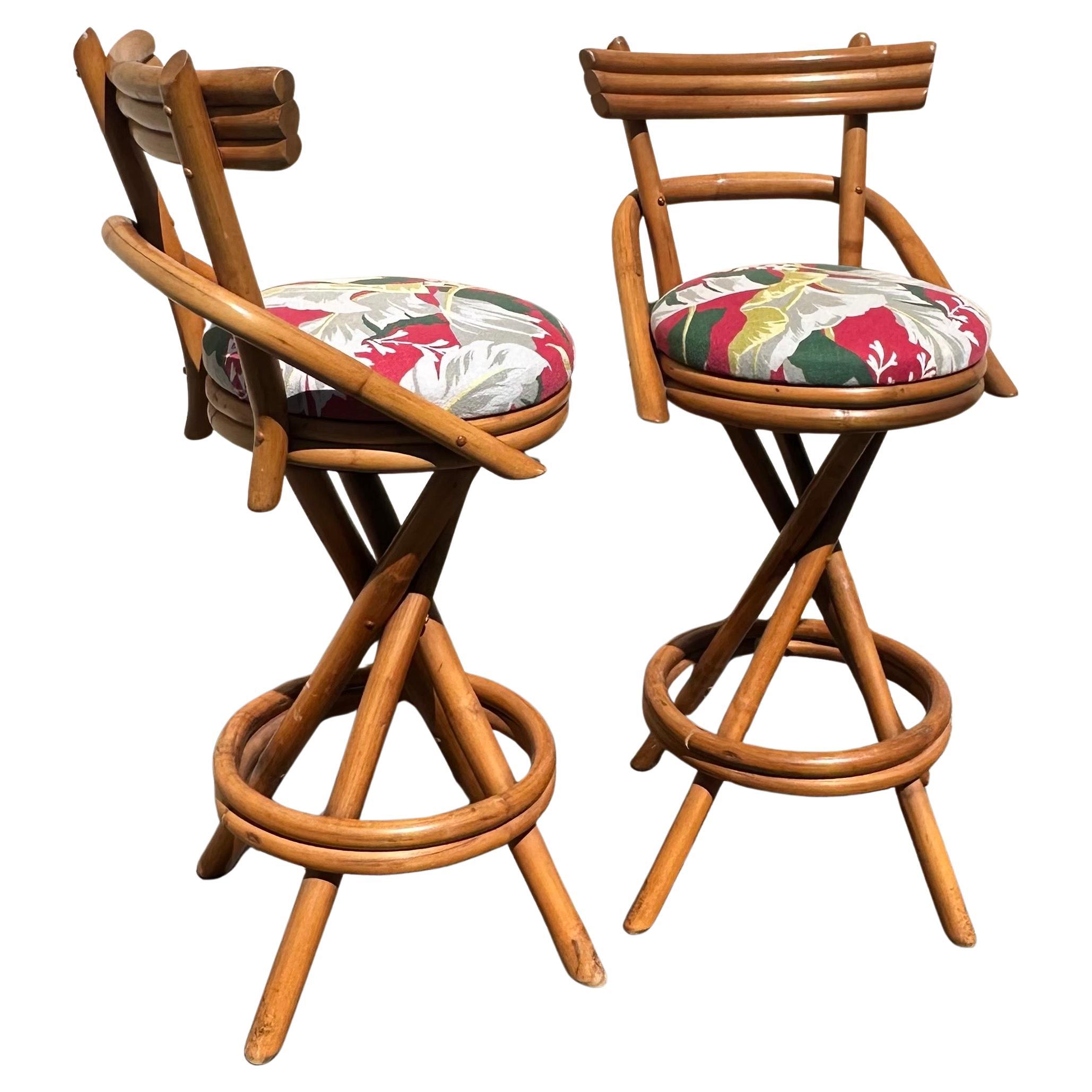 Pair of American MCM two step back rattan bar stools in the style of Paul Frankl circa 1960's.  These wonderful stools are in very good vintage condition and are finished with a bright, tropical floral upholstery.   Super cool and hard to find pair!