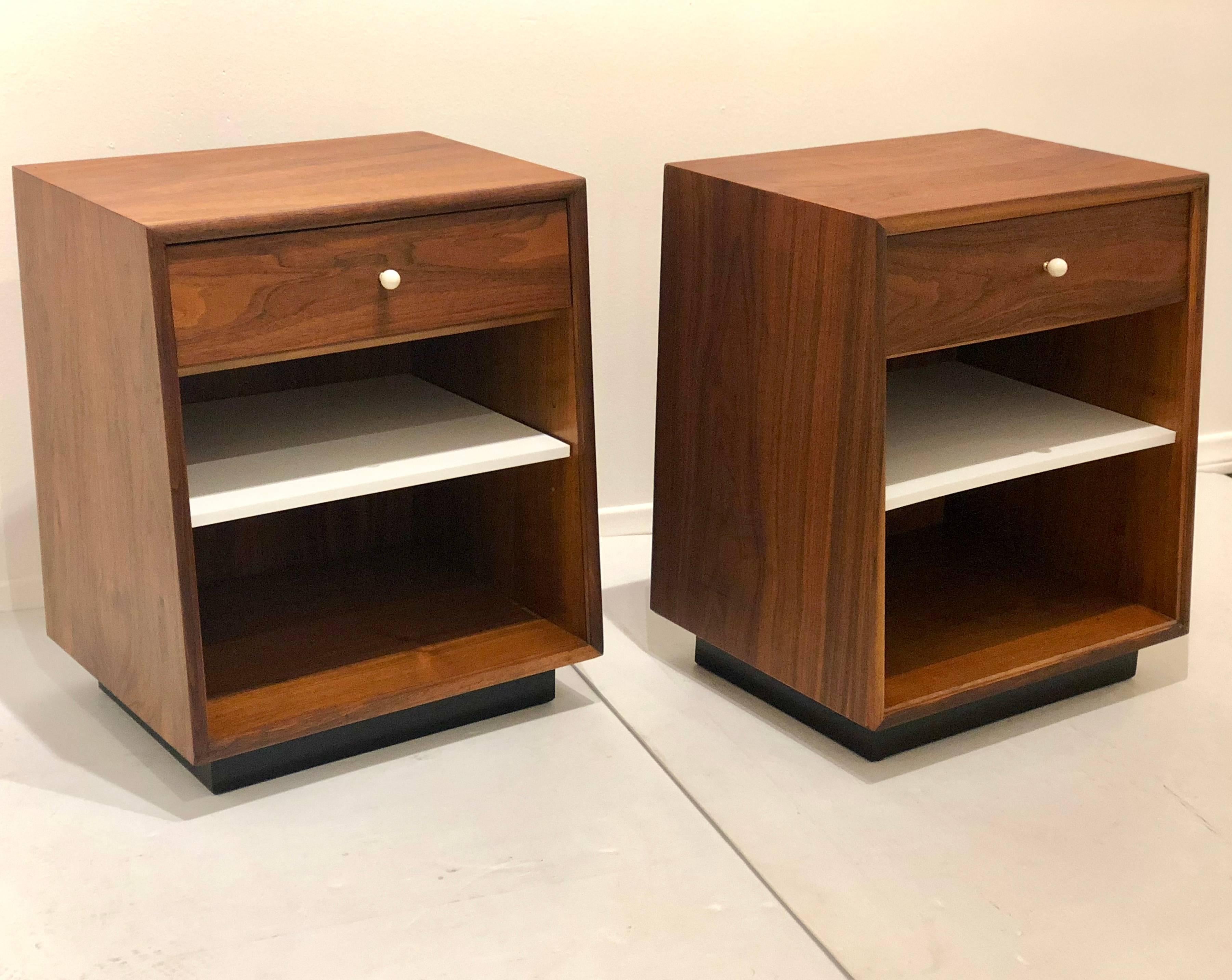 Nice pair of freshly refinished walnut nightstand by Kipp Stewart for Drexel, the bases have been sprayed in black and the middle removable shelf its in white solid plastic, to match the handle, the set its beautiful and in great condition.