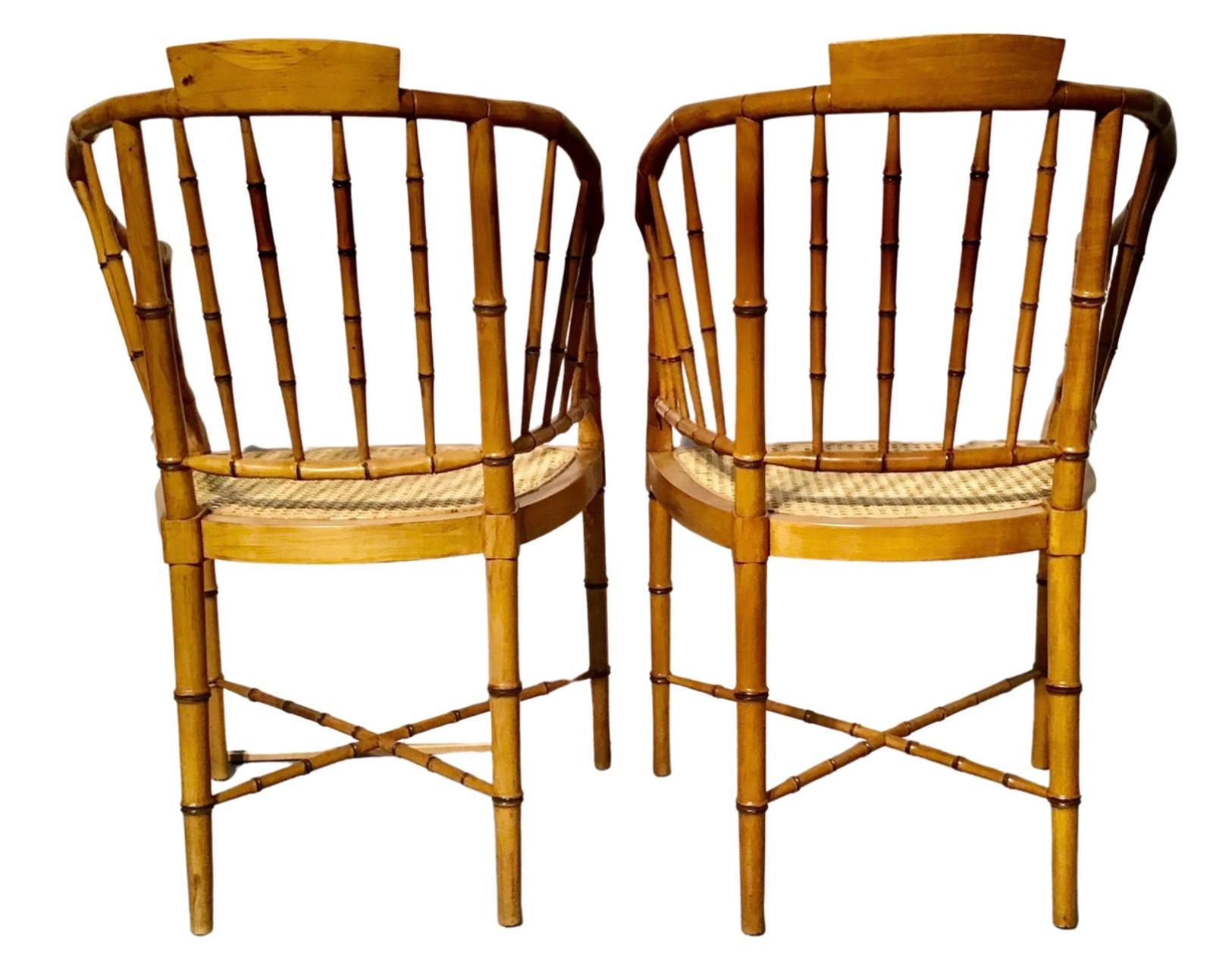 A pair of vintage Baker Furniture style faux-bamboo tub armchairs. Made of faux-bamboo, each of this pair of American Baker style chairs features a tub shaped back and curved arms resting on a cane seat. Each chair is raised on four slender legs,