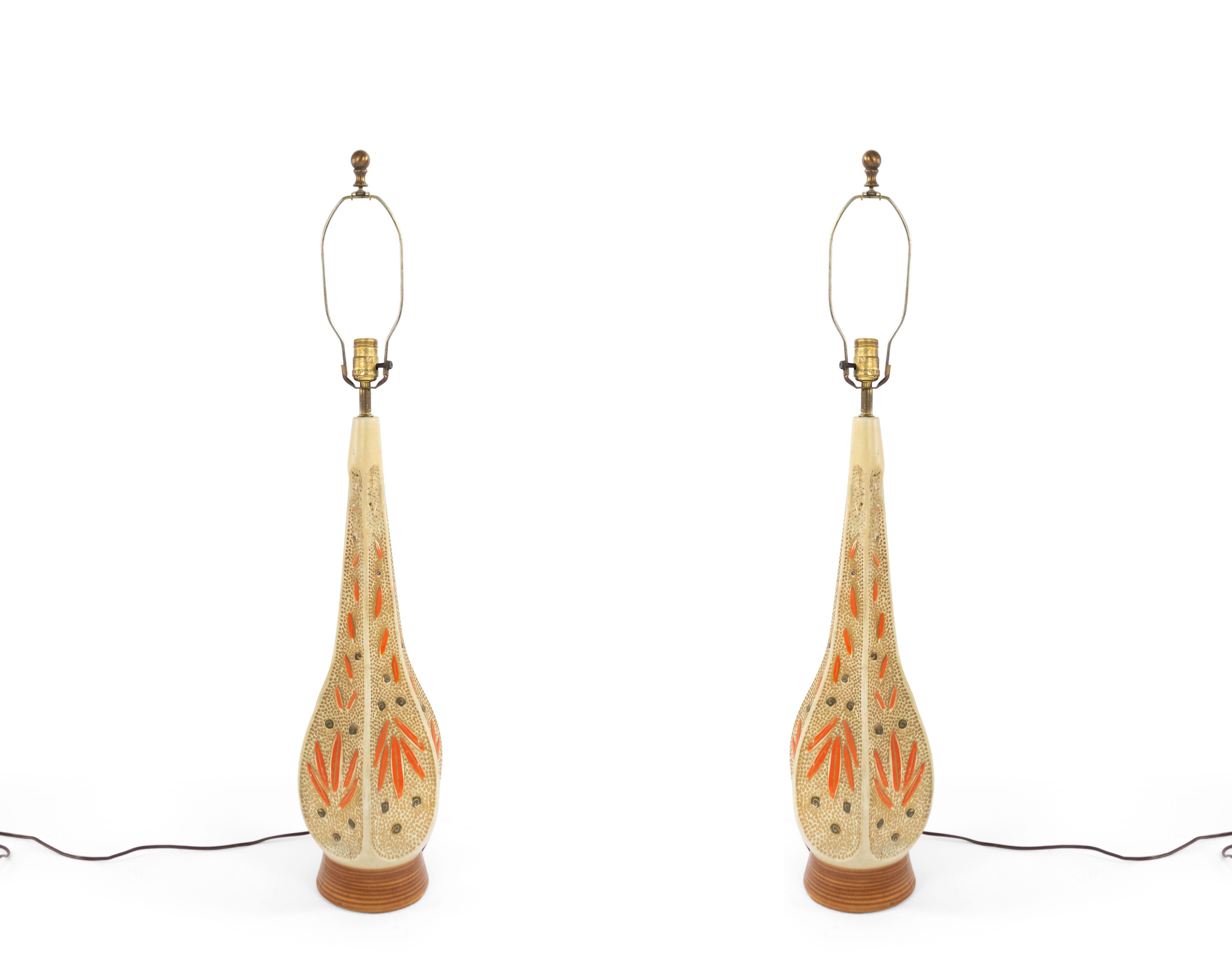 Pair of American Mid-Century beige ceramic 6 sided textured table lamps with a shaped tapered form and orange floral decoration on a round beige base (PRICED AS Pair).
