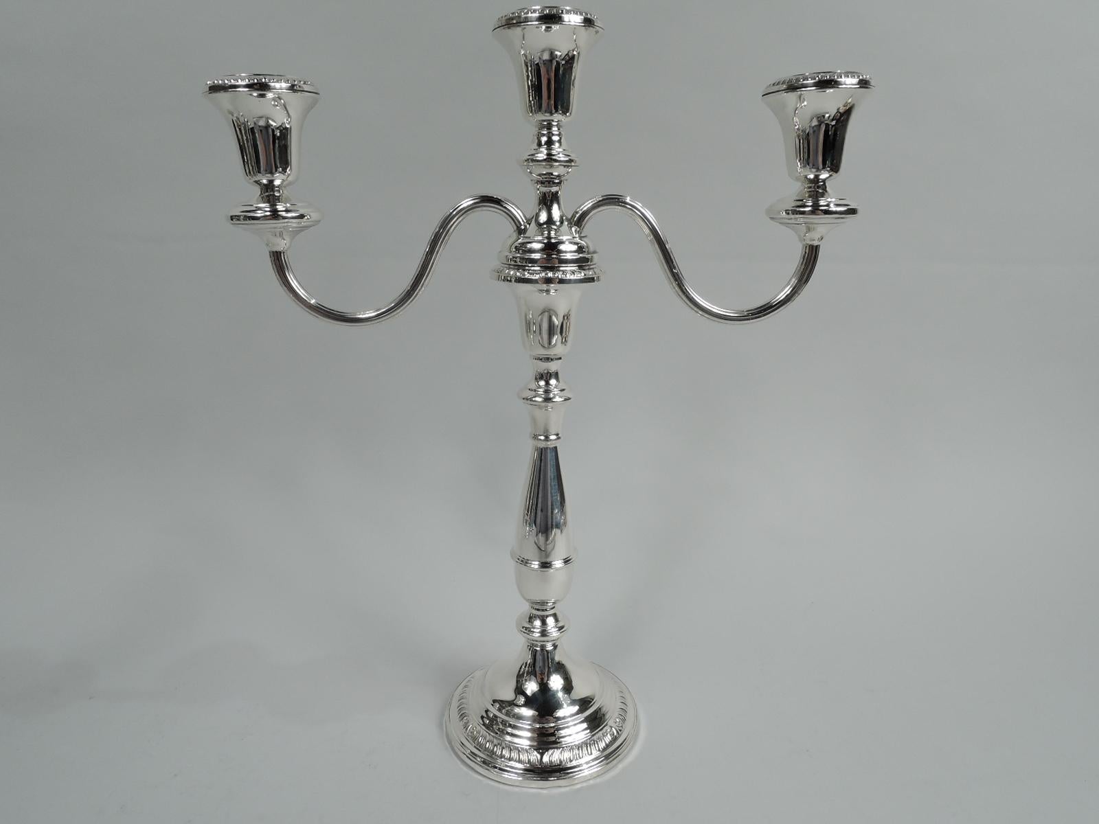 Pair of American Modern Georgian sterling silver 3-light candelabra. Each: Girdled baluster on knop on stepped and domed foot. Central socket between scrolled reeded arms, each terminating in single socket on wax pan. Gadrooning. Converts to
