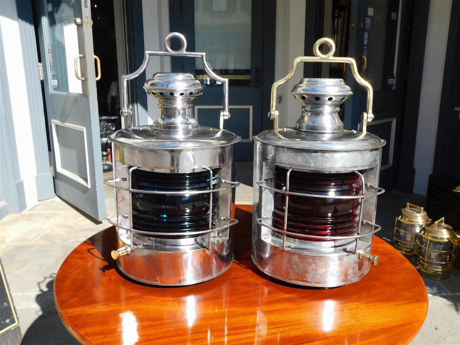 Pair of American Nautical port & starboard polished steel and brass ship lanterns with the original red and blue Fresnel lenses, flanking vented dome finials, exterior protective cages, hinged doors with rear mounts, and mounted hinged carrying