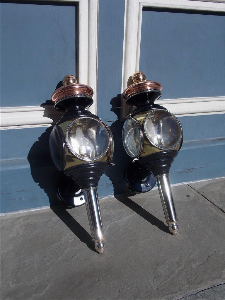 Pair of American nickel silver, copper, and brass coach lanterns with the original flanking circular beveled glass mounted on iron brackets. Lanterns were originally oil and have been electrified, early 19th century.
