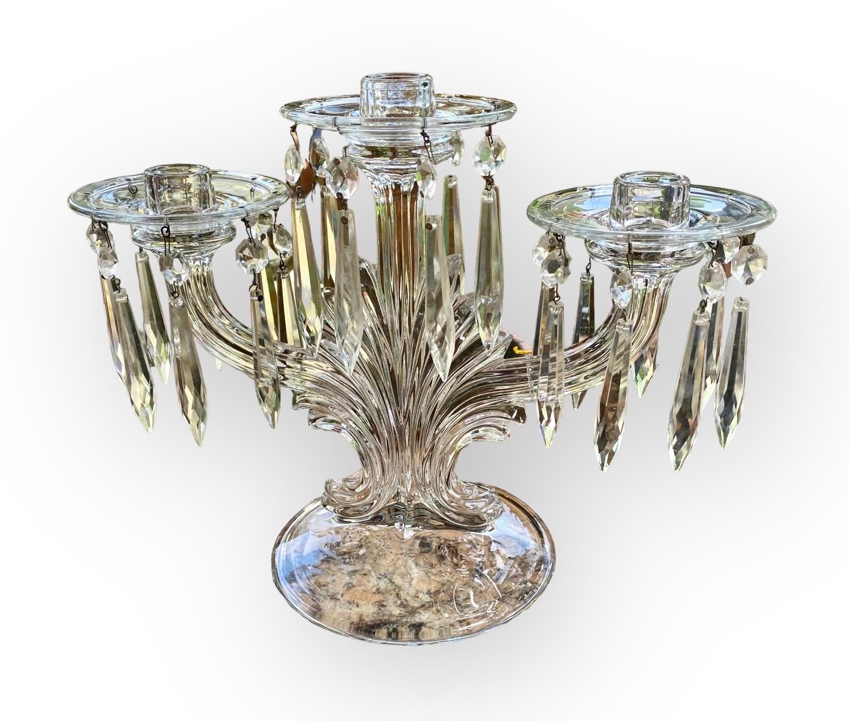 Pair of American Pressed Glass Three Light Candelabra, 2Oth c., on swirled supports with glass bobeches hung with button and spear prisms, on a domed glass base, H.- 9 1/2 in.,
W.- 10 1/4 in., D.- 6 in. Provenance: Property from a distinguished