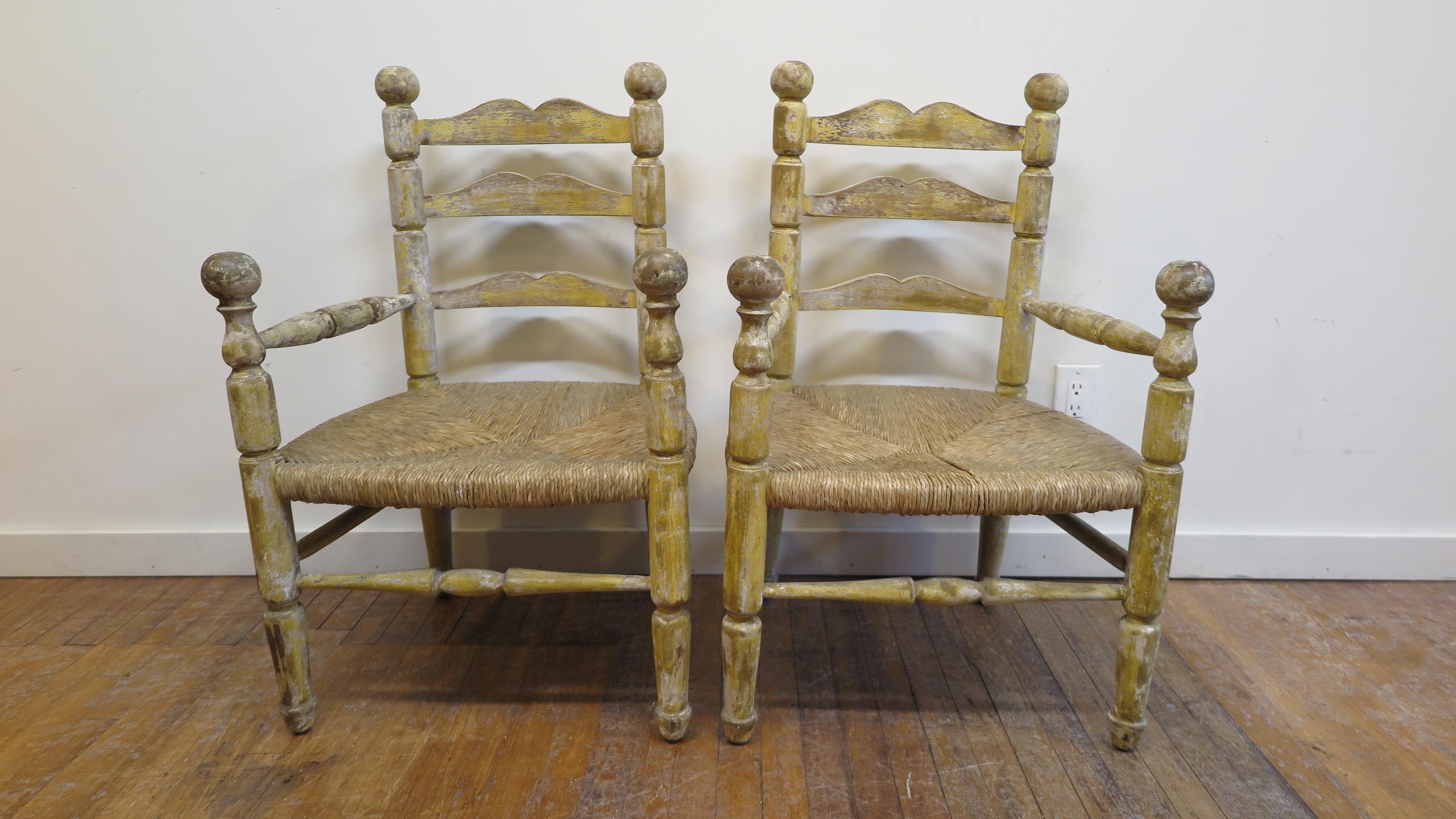 Pair of American rustic rush chairs. American antique country rush chairs with ladder backs and ball hand rests. These chairs have a seat height of 16 inches at 23 wide and 19 deep outer dimensions. Chairs are in good original condition, strong,