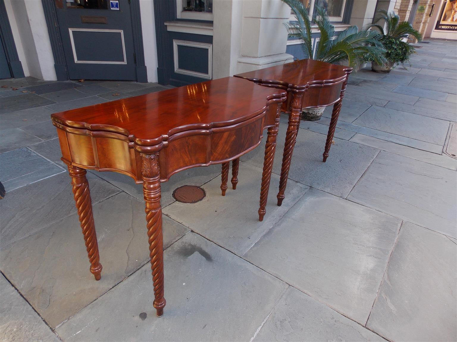 Pair of American Sheraton mahogany serpentine hinged top game tables with one board tops, outset corners with acanthus carved motif,  carved molded edge skirt, swivel hinged gate leg, and terminating on the original bulbous ringed barley twist legs,