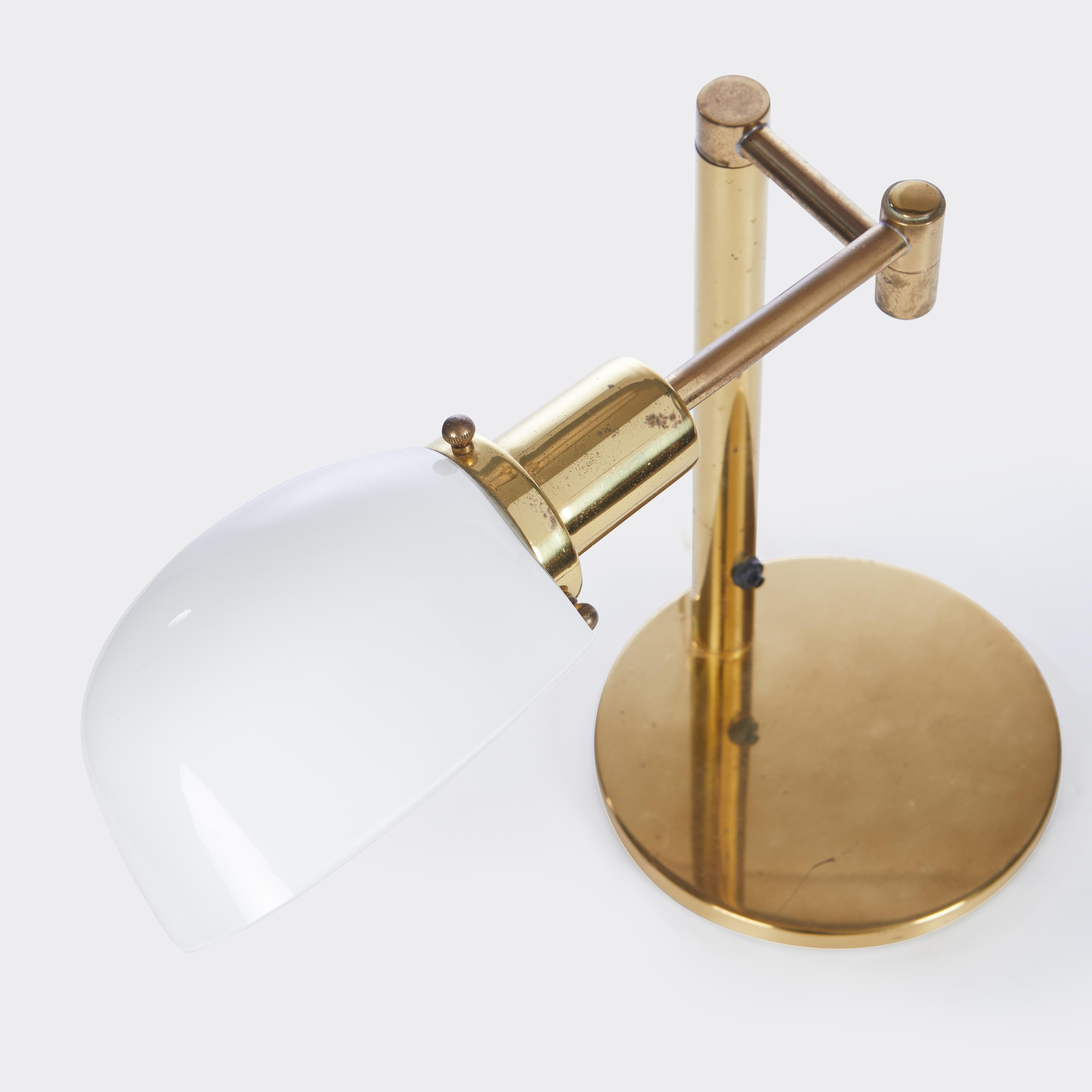 A pair of American swing arm table lamps with white opaline glass shades in polished lacquered brass with weighted bases. by Nessan and Co.