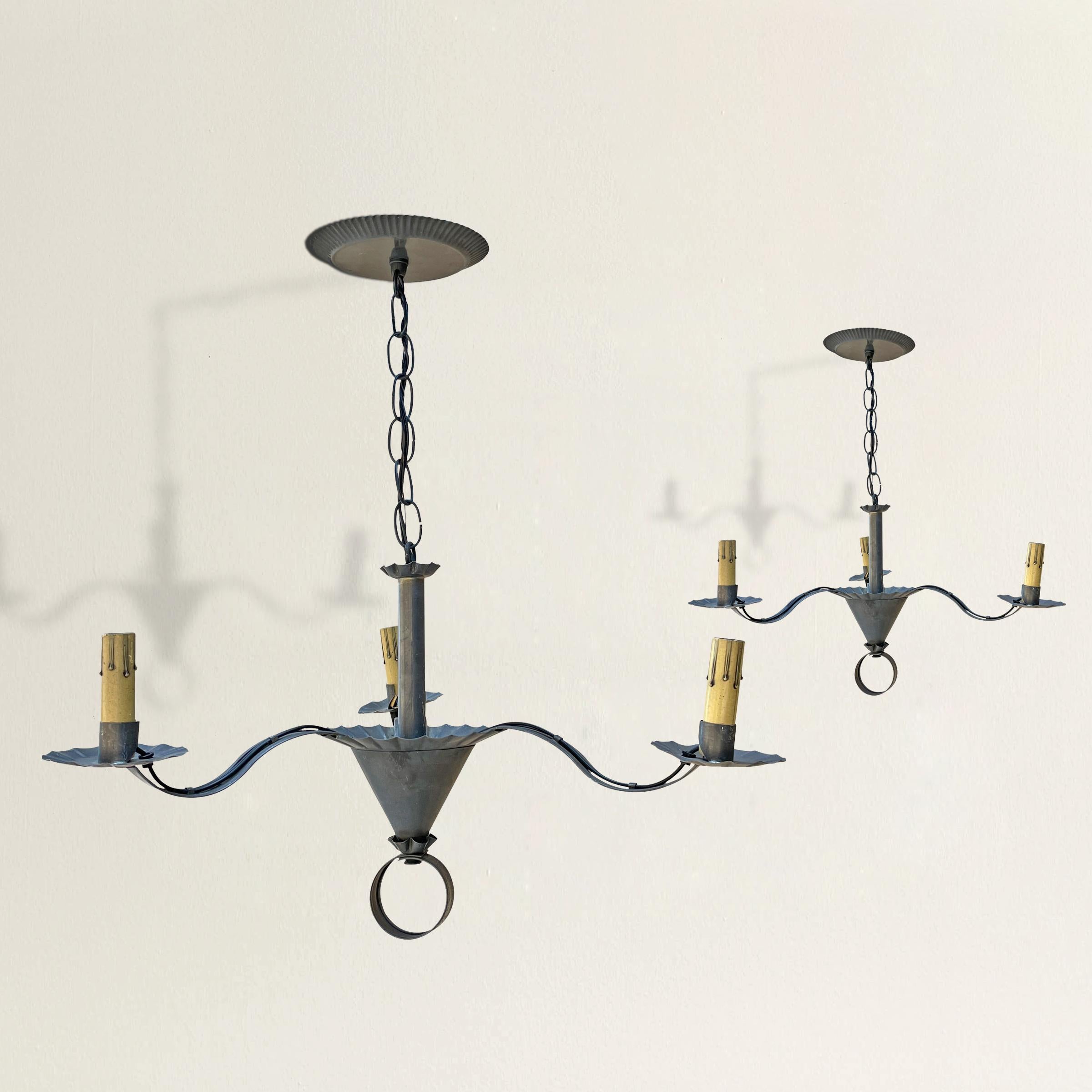 A charming pair of American tin three-arm chandeliers with conical bodies, pie-crust ruffled candle cups, and rings at the bottom of each. Wired for US with chandelier base sockets. Canopies included.