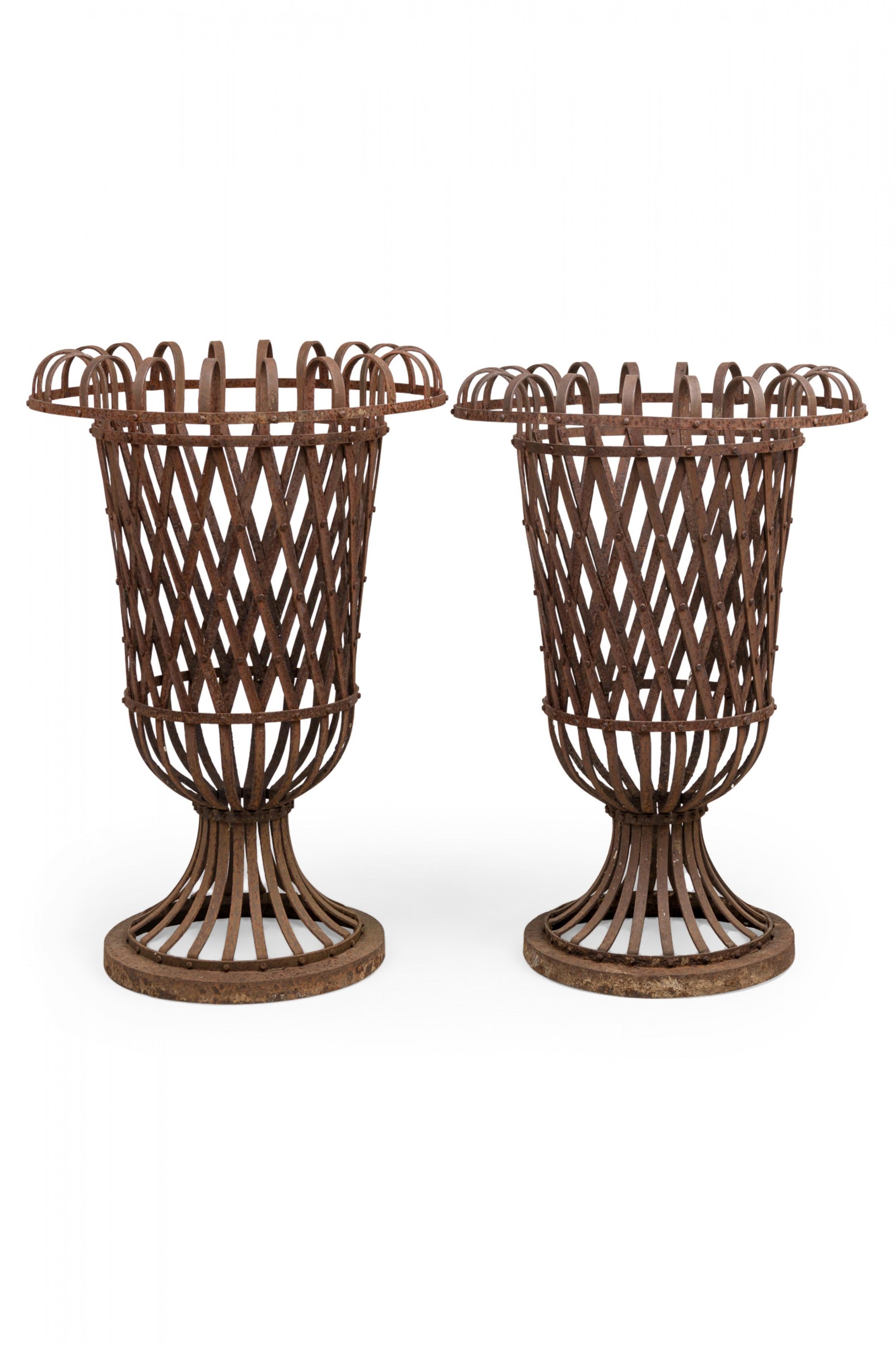 Paire d'urnes de jardin de style victorien américain (fin du 19e siècle/début du 20e siècle) en forme de balustre en fer forgé patiné par les intempéries, avec un motif de treillis tissé qui s'enroule sur le dessus. (PRIX PAR Paire)

La corrosion et