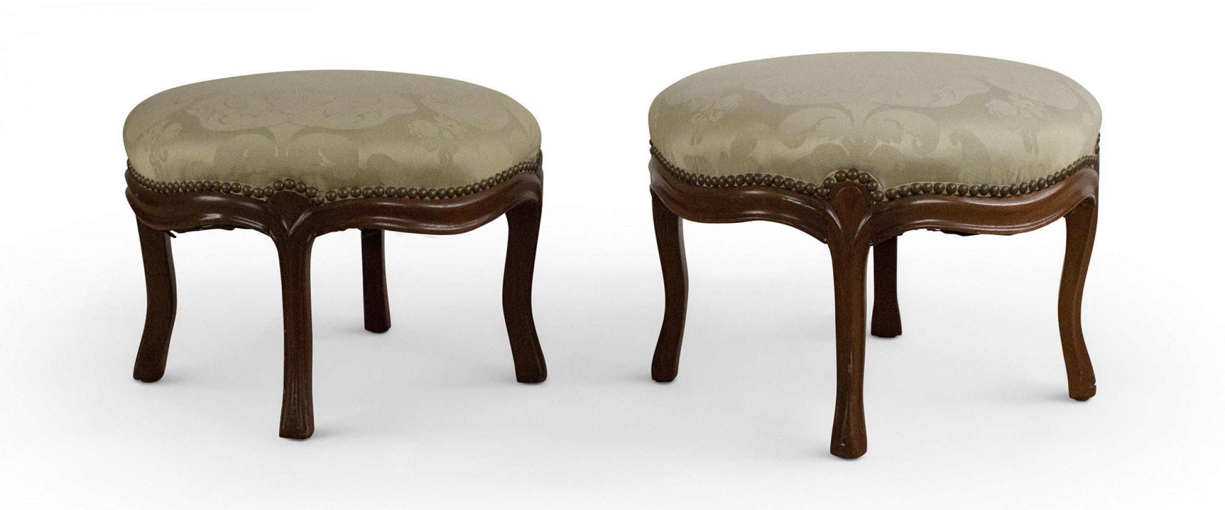 Pair of similar American Victorian footstools with carved walnut frames and light green damask upholstery with brass nail head trim. (priced as pair).
      