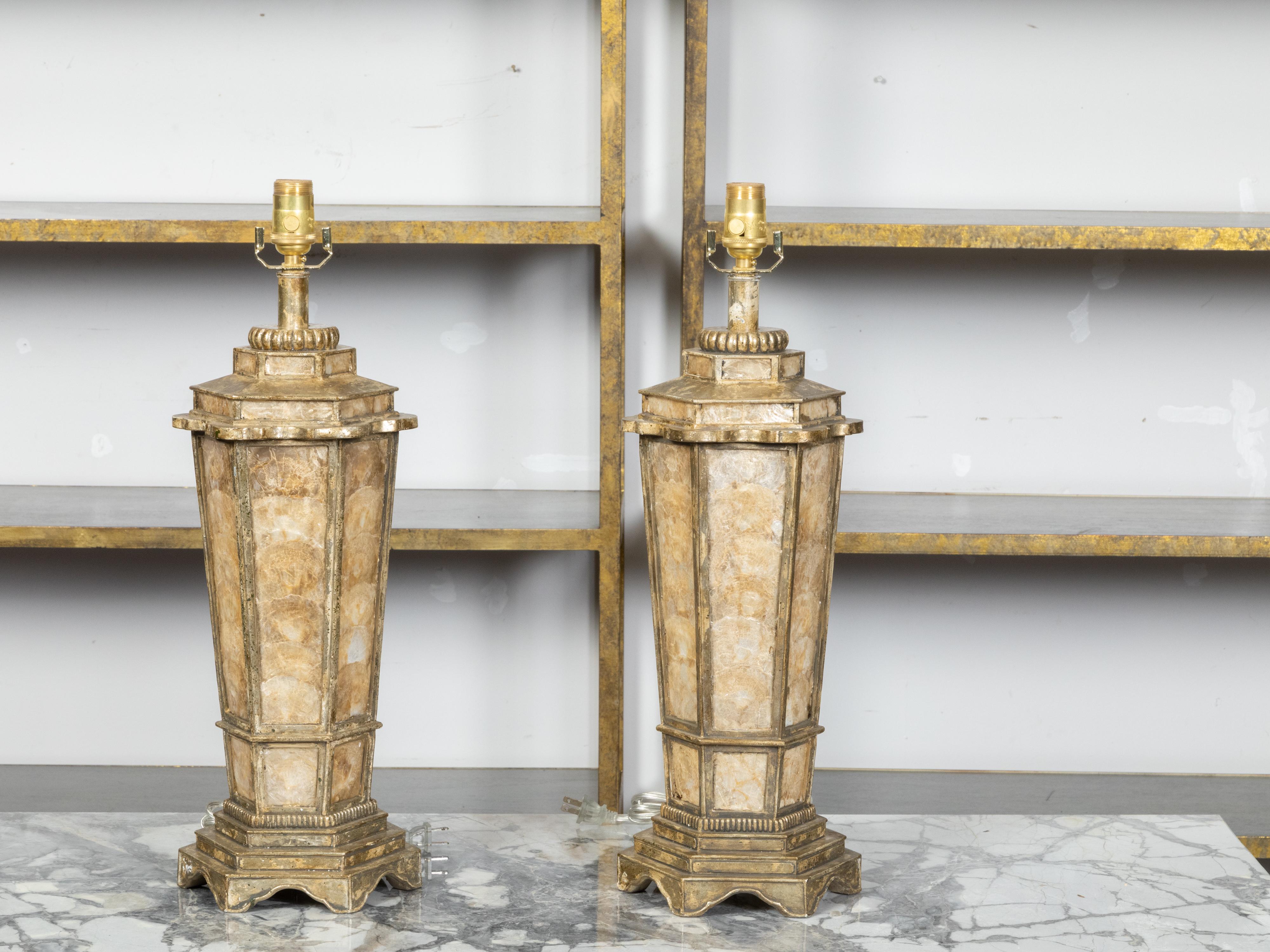 A pair of vintage American table lamps from the late 20th century, with hexagonal bodies, shell décor and gilded accents. Made in the USA during the last quarter of the 20th century, each of this pair of table lamps features an hexagonal tapering