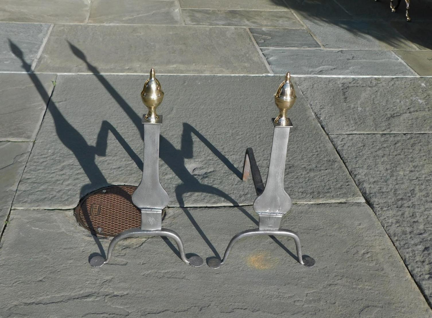 Pair of American wrought iron knife blade andirons with flanking brass acorn finials, squared plinths on scrolled legs, and resting on the original penny feet. early 19th century.