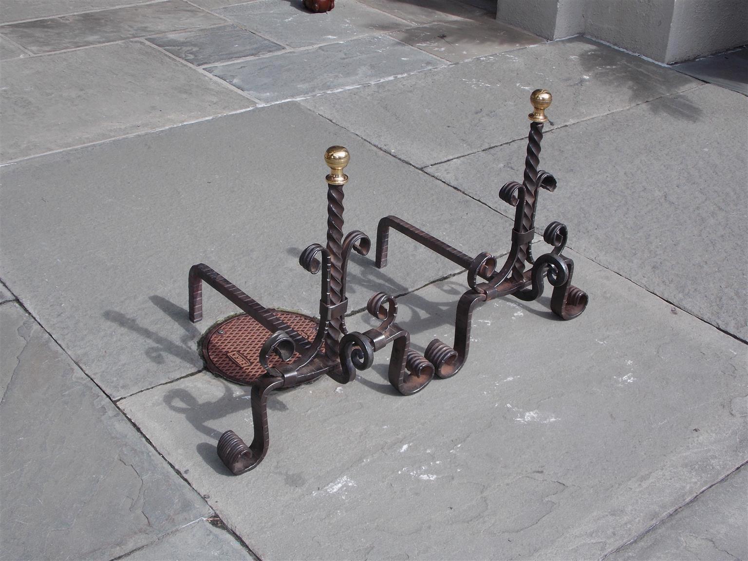 Pair of American wrought iron and brass ball top diminutive andirons with centered spiral columns, scrolled plinths with spit hooks, original chased dog legs, and resting on decorative scrolled chased feet, Mid-19th century.