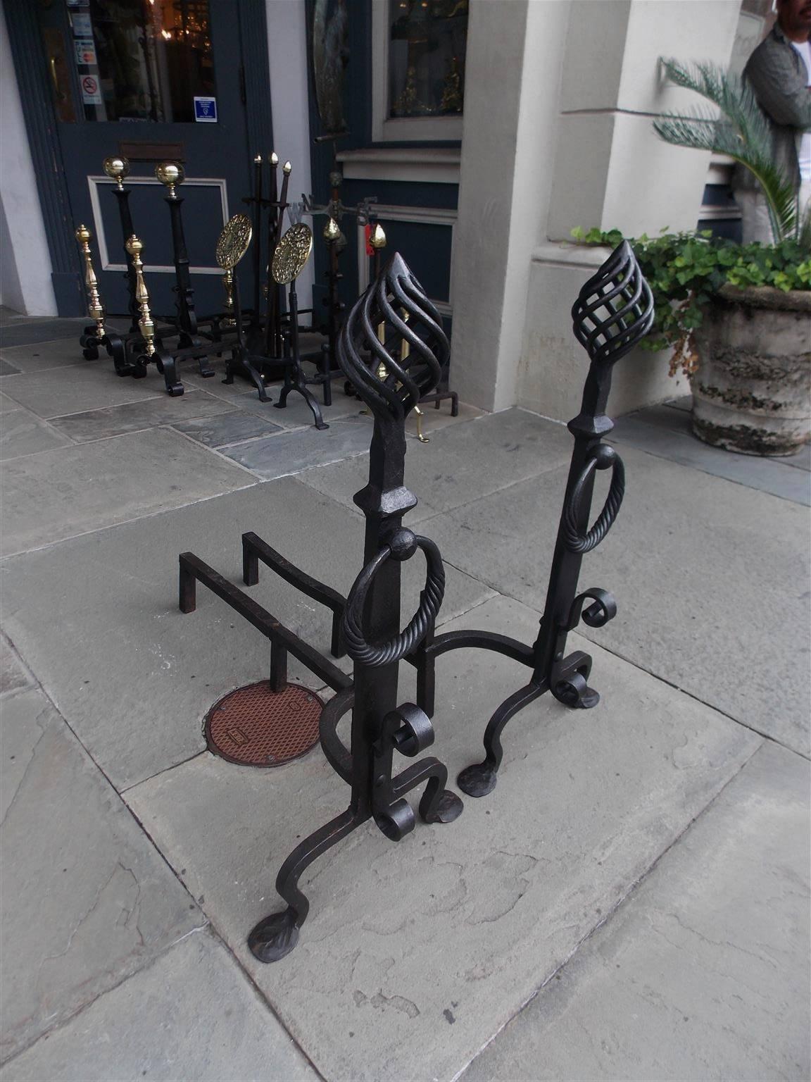 Pair of American wrought iron andirons with birdcage spiral finials, squared tapered plinths, flanking decorative rope rings, scrolled spit hooks, matching faceted log stops, and terminating on hand-hammered penny feet, Early 19th Century.