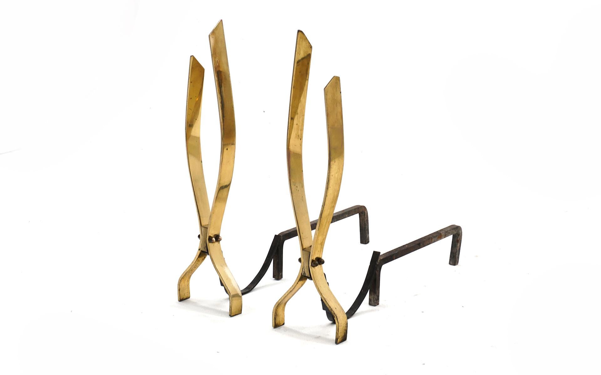 Pair of vintage andirons in brass plated steel and iron in the style of Donald Deskey. Very good condition and ready to use. We can pack and ship these in the Continental US arriving to you within two weeks.