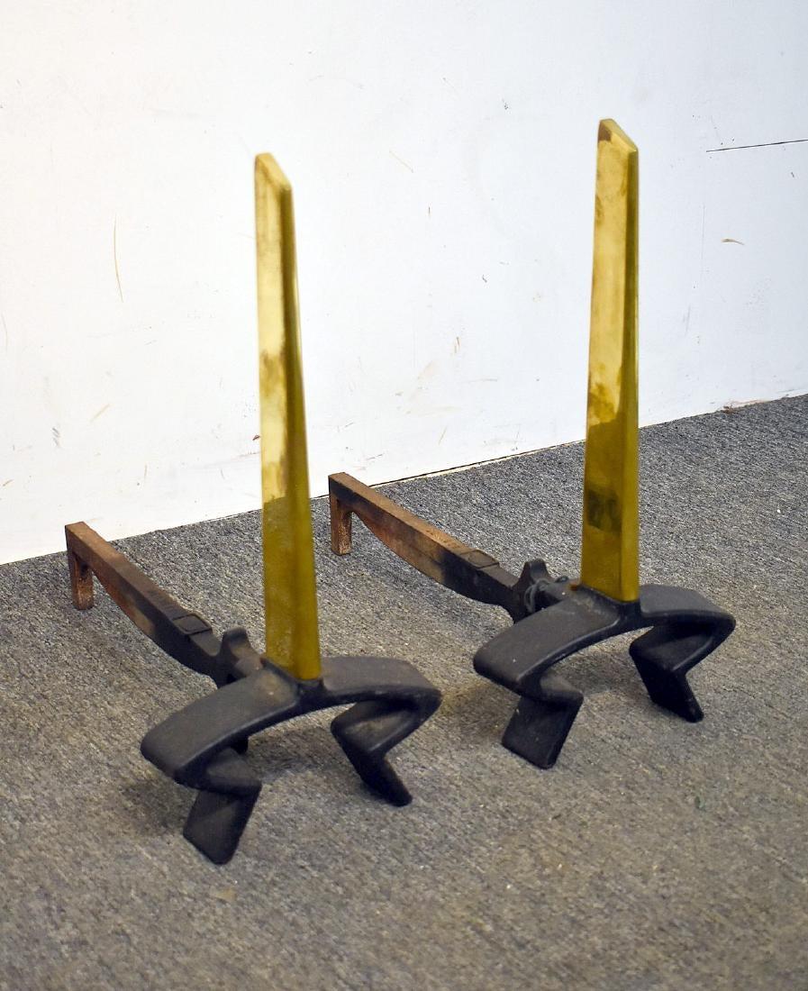 A pair of andirons designed by Donald Deskey for Bennett, USA, circa 1950. Polished brass with black iron supports.