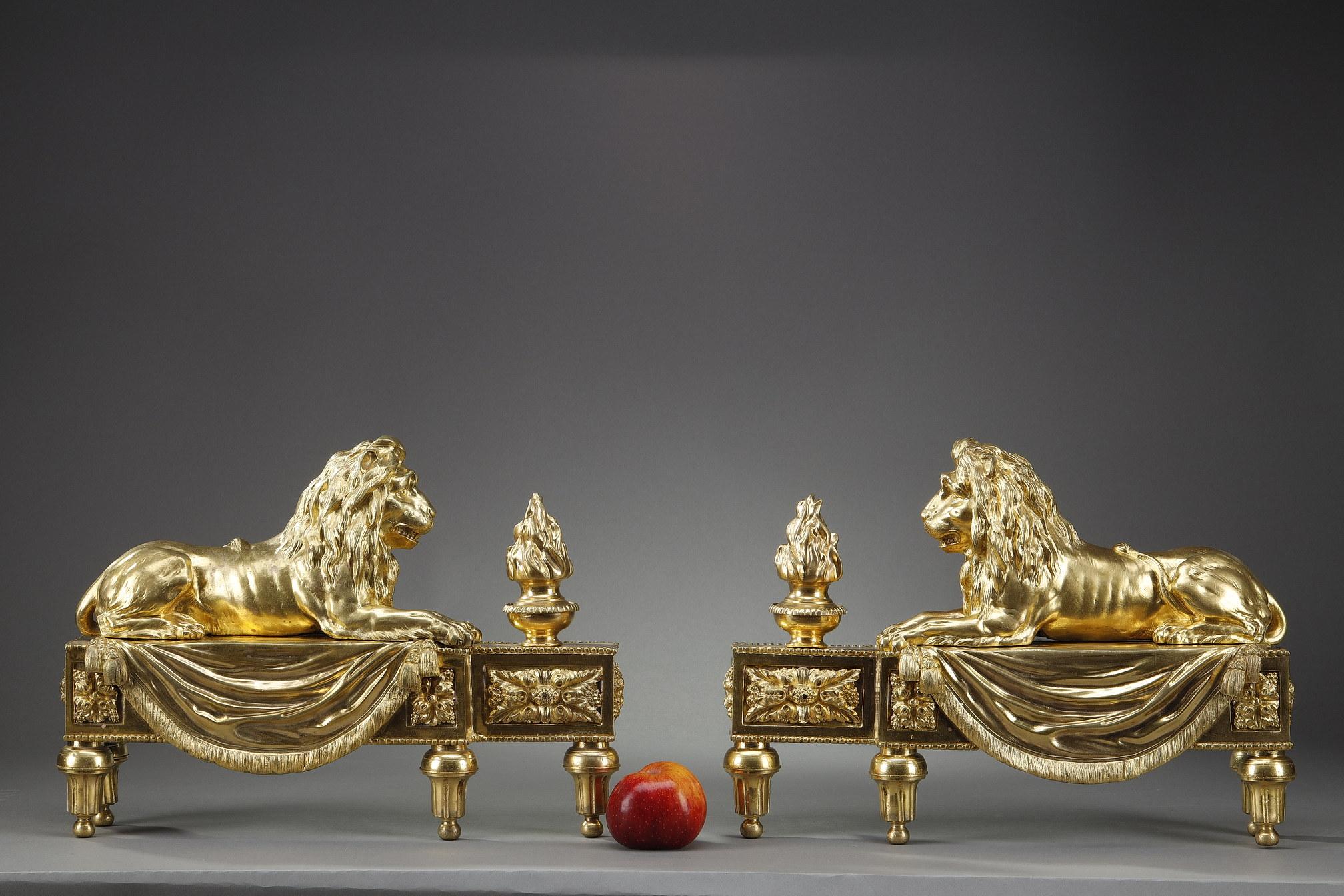 Large pair of gilt and finely chiselled bronze andirons in the Louis XVI style. They are surmounted by laying lions on a drape decorated with trimmings facing fire pots. The animals are very well worked with nervous limbs, detailed manes and exposed