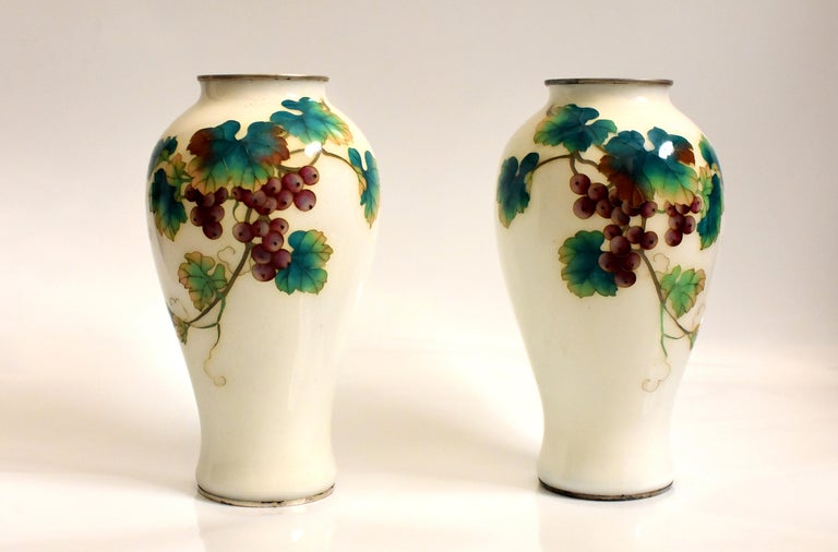 A rare offering of a pair of beautiful, vintage, grape themed Ando Jubei over-glaze Cloisonne vase. Elegant form, perfect proportions and the finest finish in high gloss. Rim and base encased in silver metal. Ando Jubei, one of Japan's most