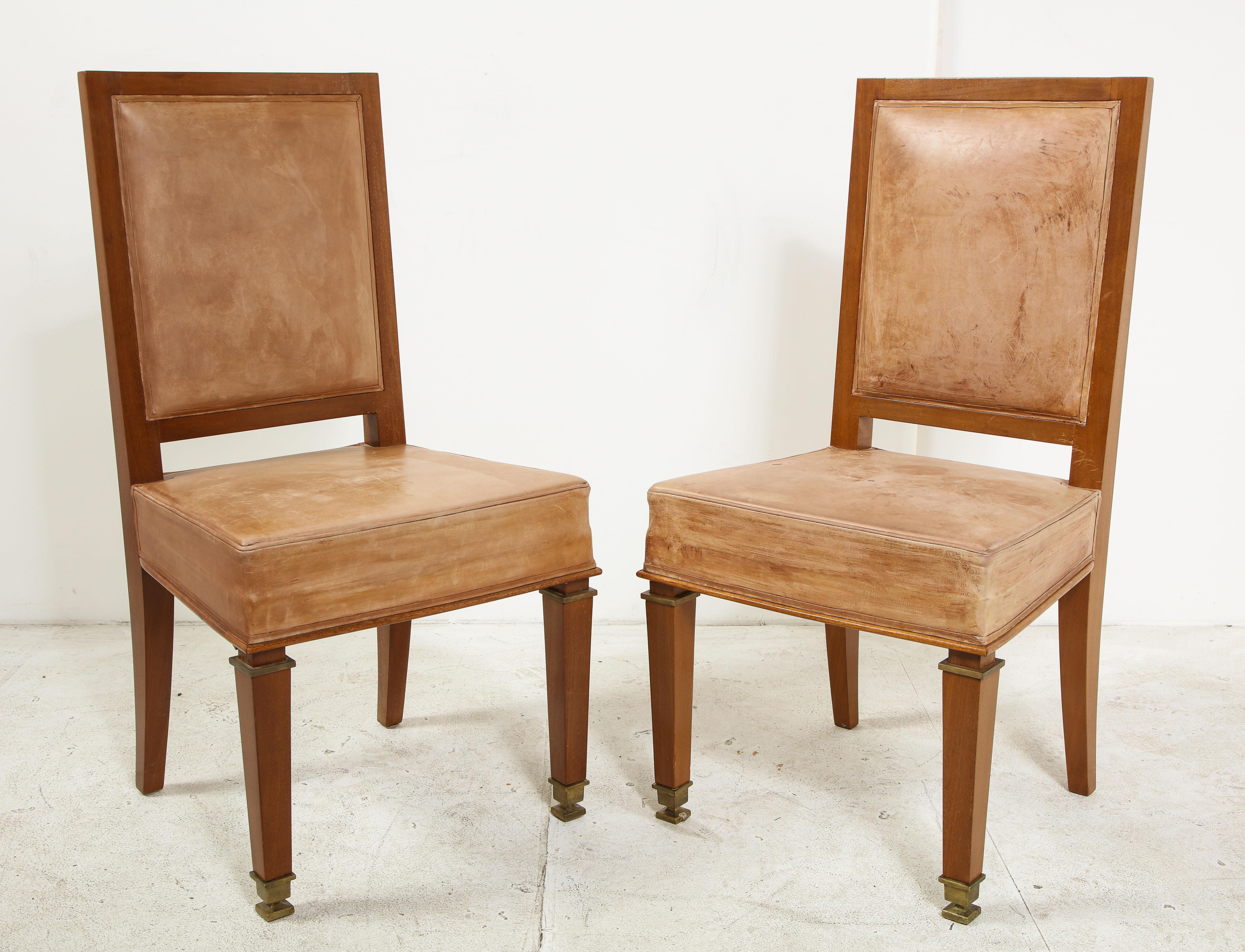 An immaculate pair of cerused oak side chairs by André Arbus with tan leather seat and back. Brass caps and carved details on the front legs.