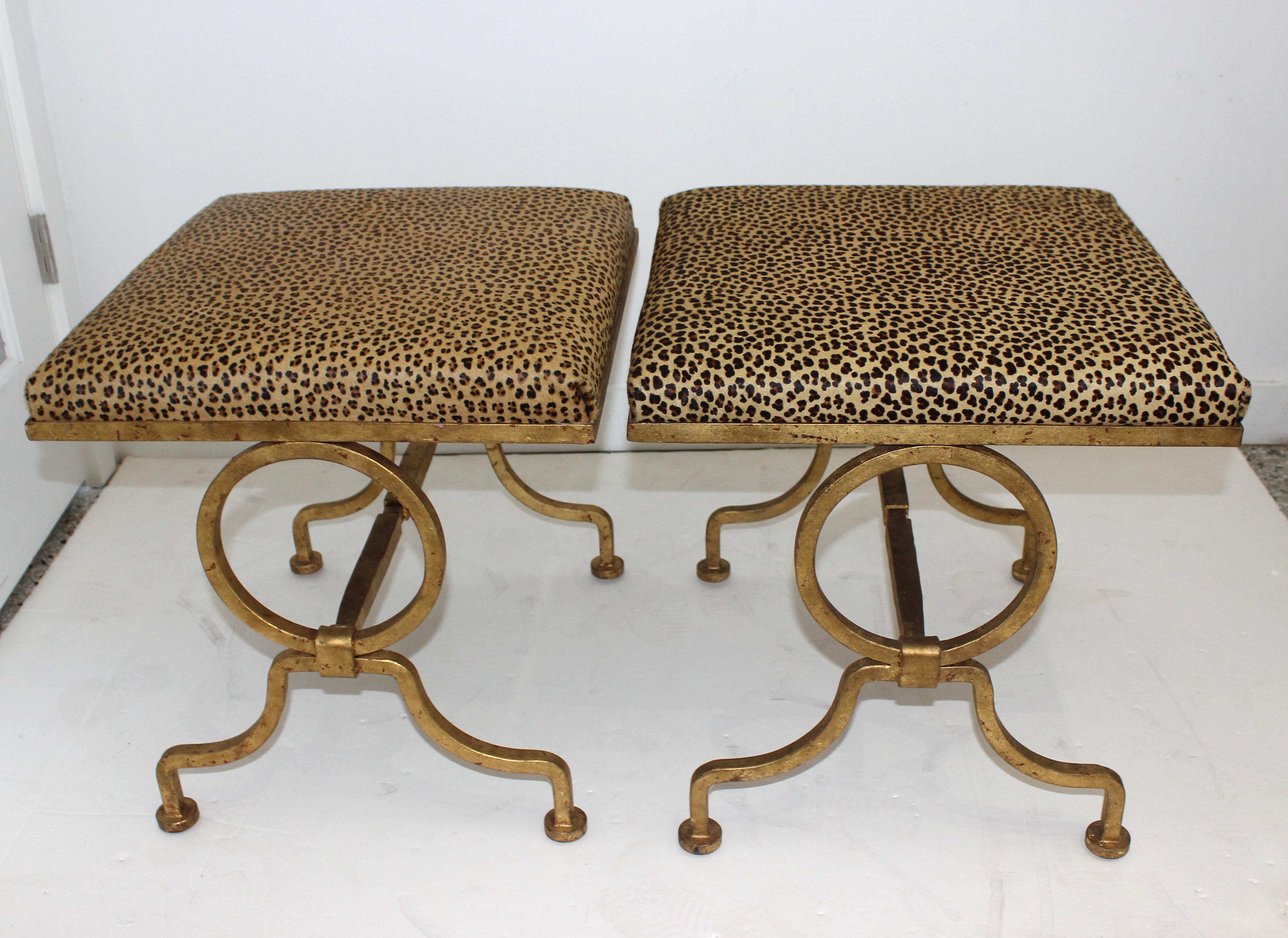 This stylish pair of stools date to the midcentury and are very much in the quality and style of pieces created by Andre Arbus. The faux leopard motif cow hide upholstery compliments the gilded metal finish.