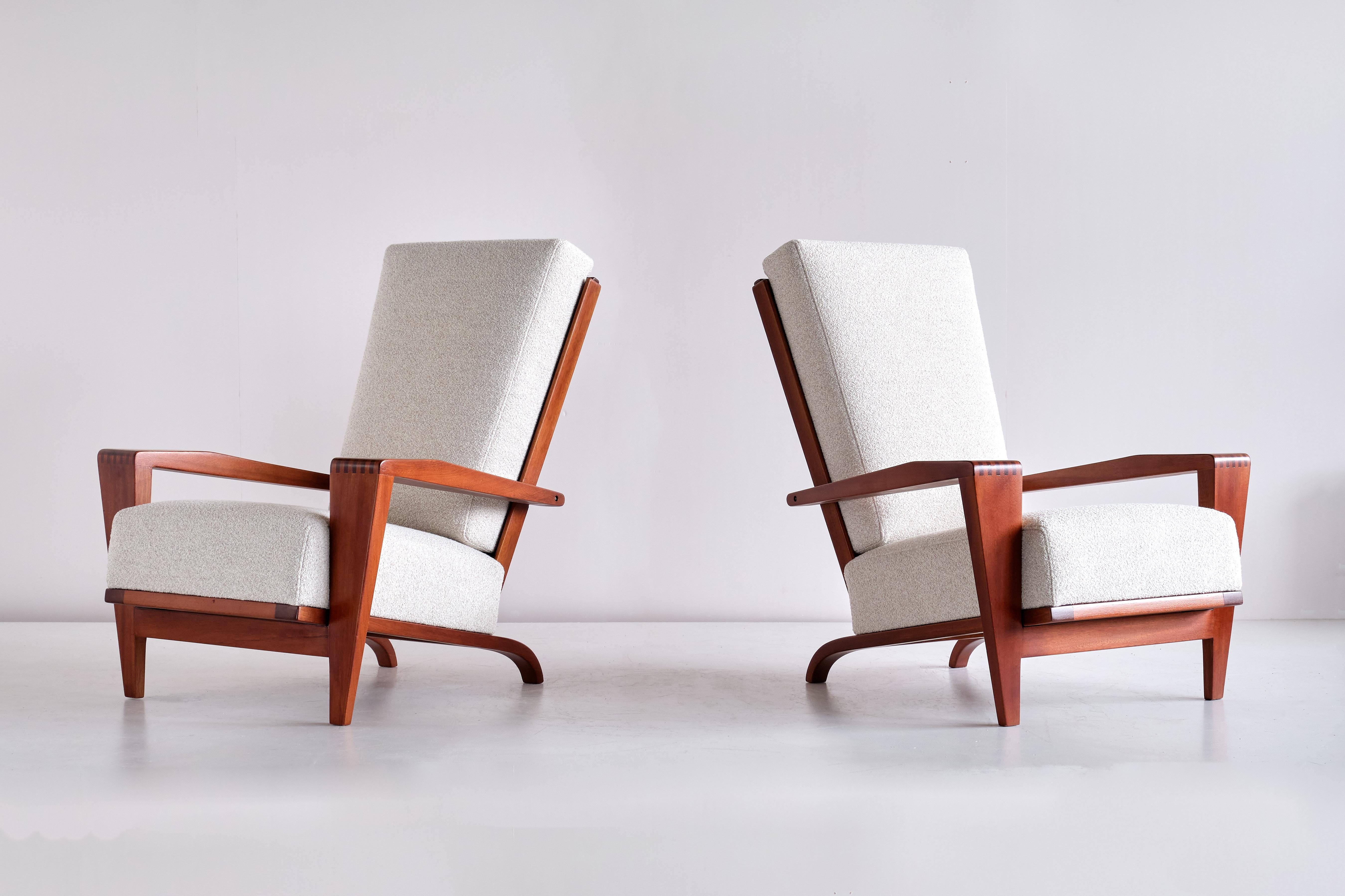 This rare pair of armchairs was designed by André Sornay and produced by his workshop in Lyon in the early 1950s. High, angled backrest in sapele mahogany with upholstered cushions. Both the armrests and front legs are in a trapezium shape and are