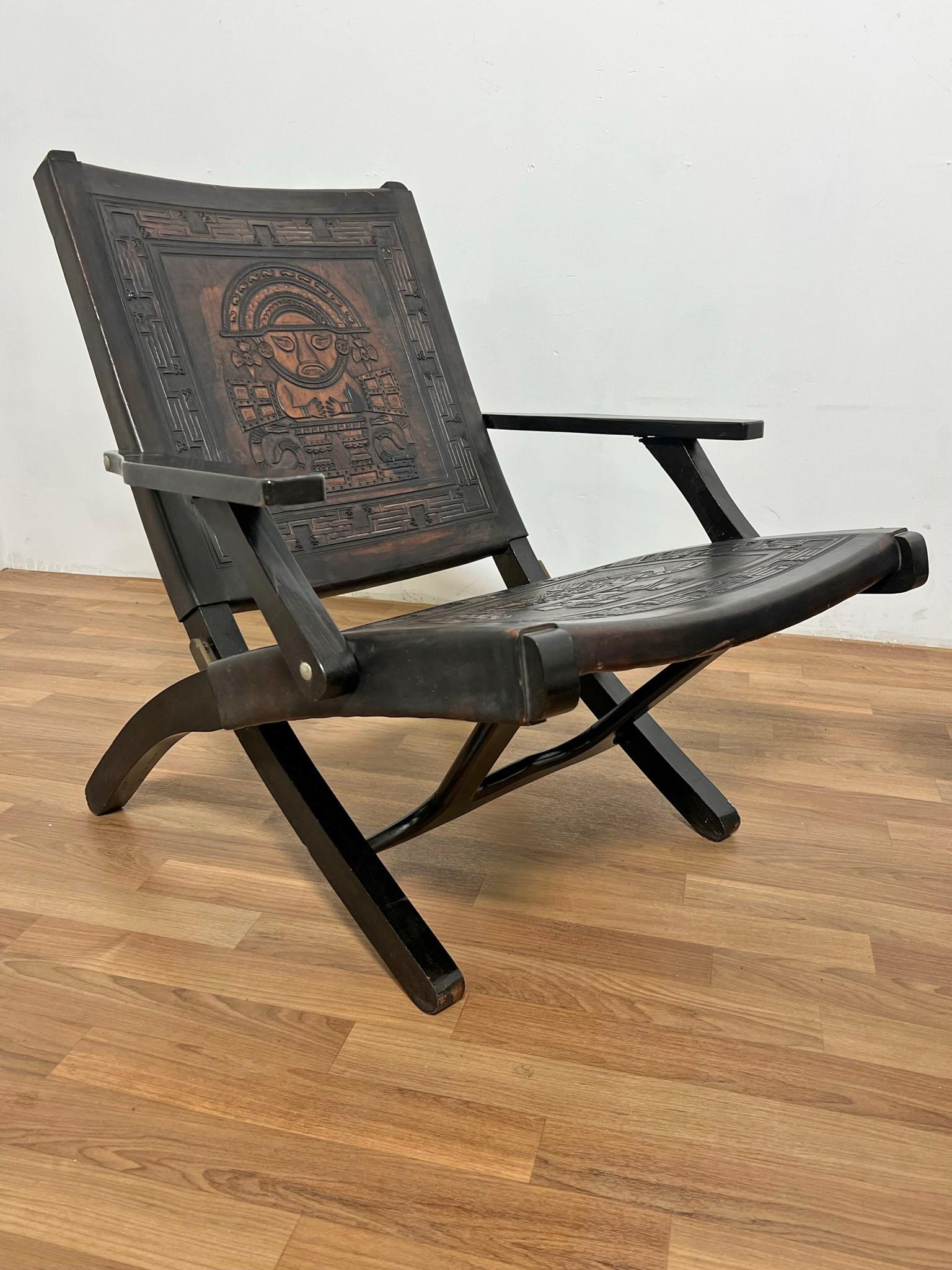 Pair of folding leather safari arm lounge chairs by Angel Pazmino for Muebles De Estilo of Ecuador, circa 1960s. These feature leather seats and backs adorned with the Incan hand tooling typical of Pazmino's designs.


