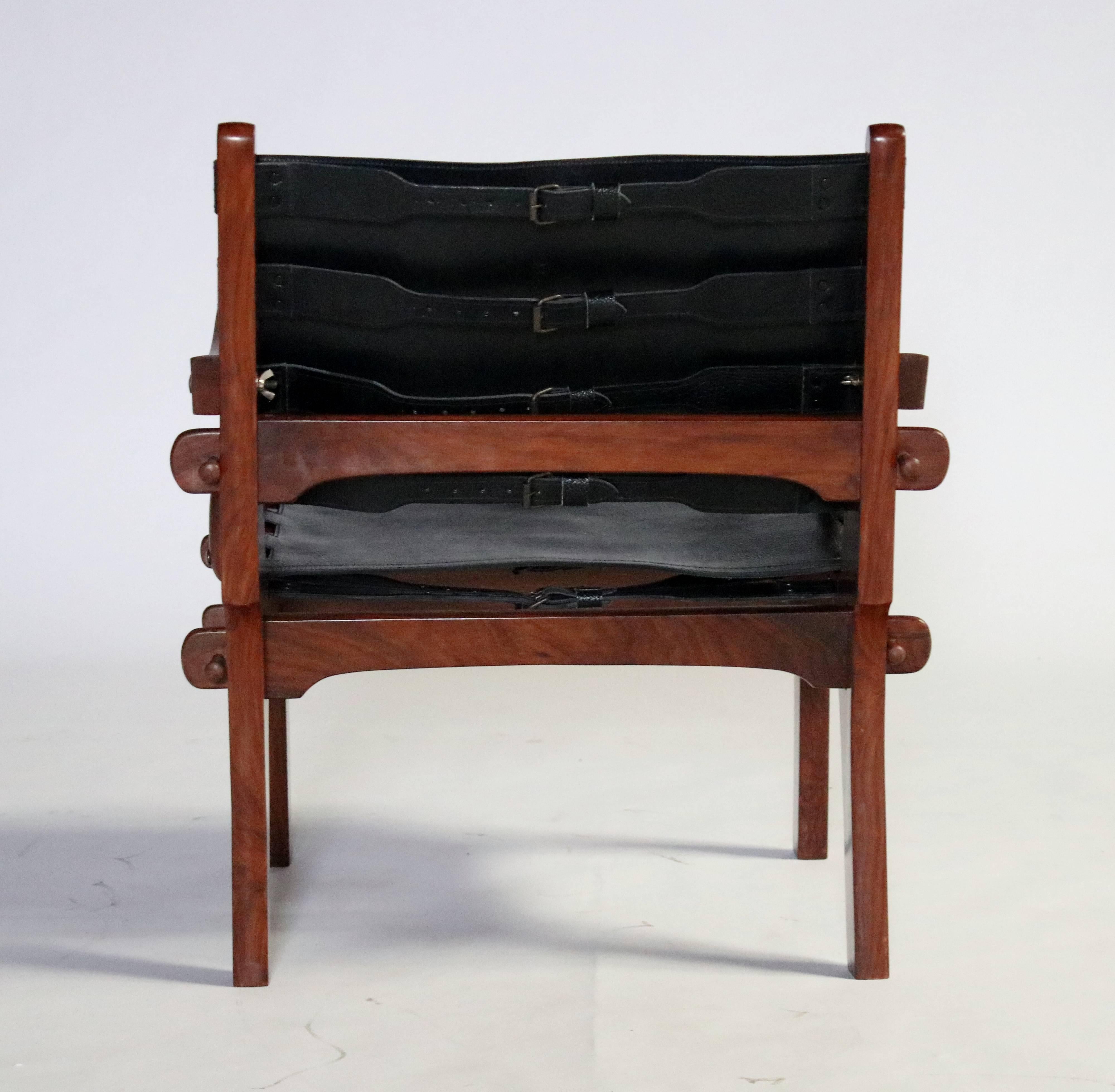 Pair of Brazilian rosewood and black leather sling armchairs with corset straps by Angel Pazmino. These chairs were purchased in Rio and have been stored for over 20 years appearing to never been used. Designed from a wooded peg construction which