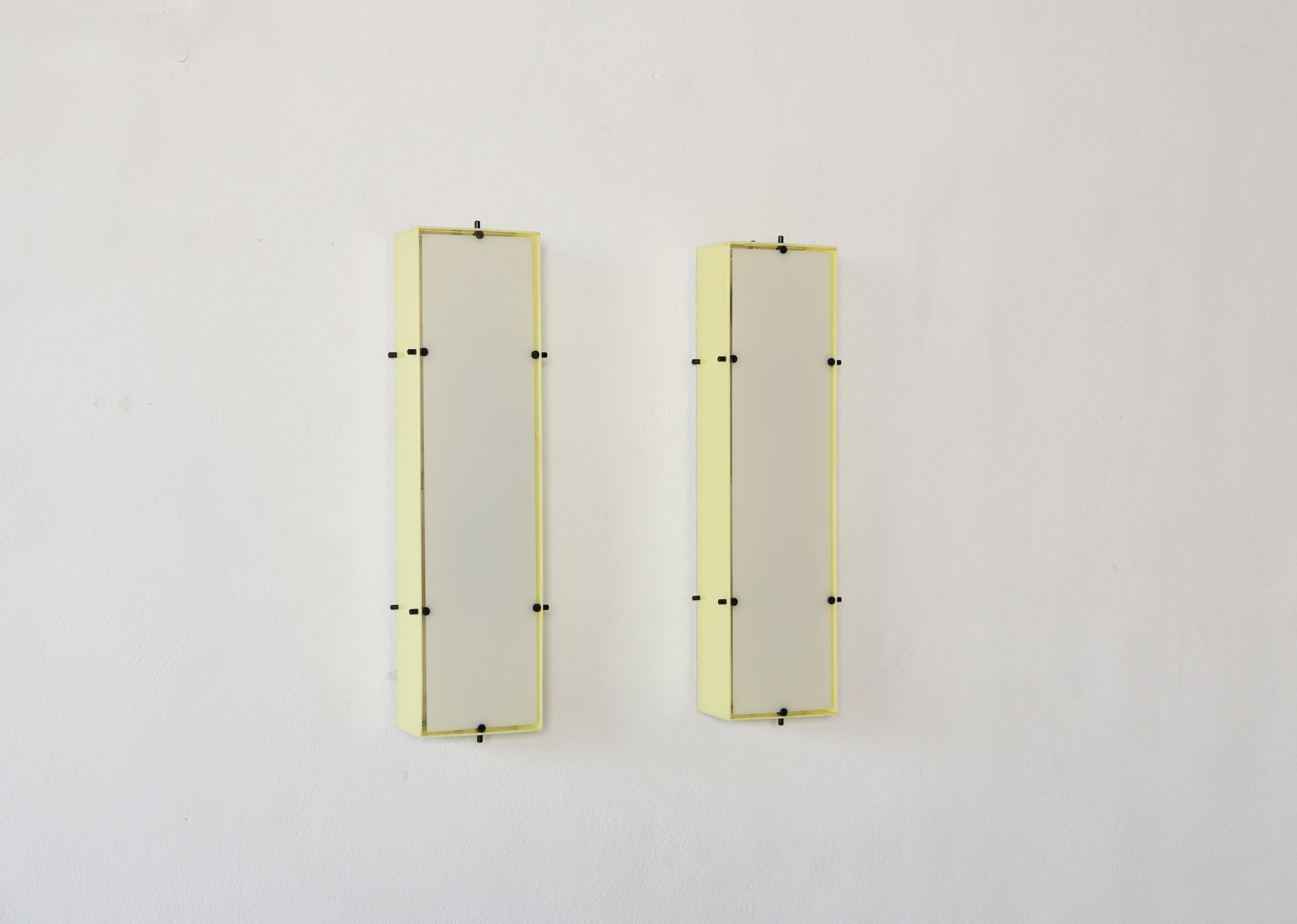 A rare pair of wall sconces / lamps designed by Angelo Lelii for Arredoluce, Italy, 1950s.   Metal backplate with yellow plexiglass sides and white plexiglass front.   Original makers labels present.  Fast shipping worldwide.

