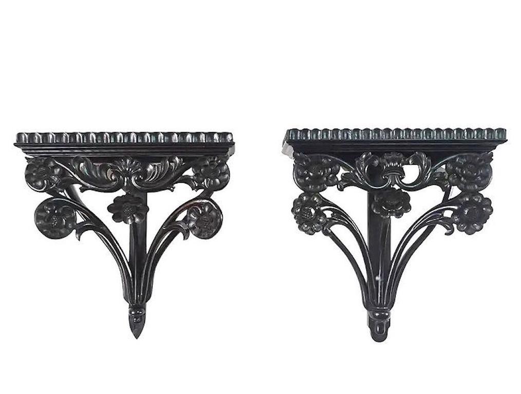 An associated or 'collected pair' of second quarter 19th century British Colonial, Anglo-Ceylonese / Anglo-Indian carved ebony wall brackets / shelves / sconces of large scale having shallow fluted-edge gallery platforms surmounting floral and