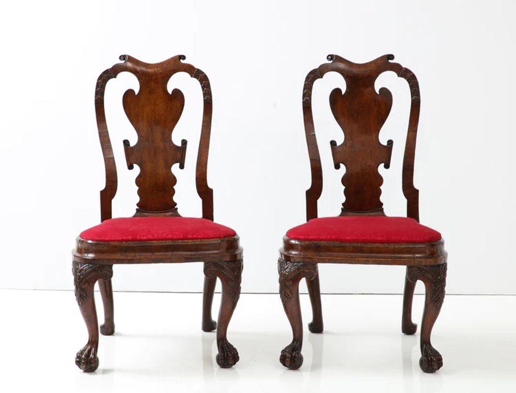 Rara e insolita coppia di poltroncine anglo-olandesi in noce, con una sponda superiore a sella su uno schienale impiallacciato, i montanti intagliati con fiori a campana, una seduta modellata a forma di palloncino con gambe a cabriola anteriori
