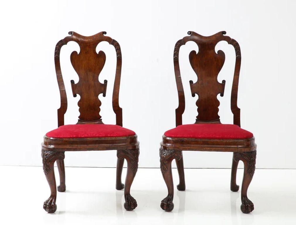 A rare and unusual pair of walnut Anglo-Dutch side chairs with a saddle chest top rail over a veneered back splat, the stiles carved with bell flowers, having a molded, balloon-shaped seat with front carved cabriole legs, having carved knees and