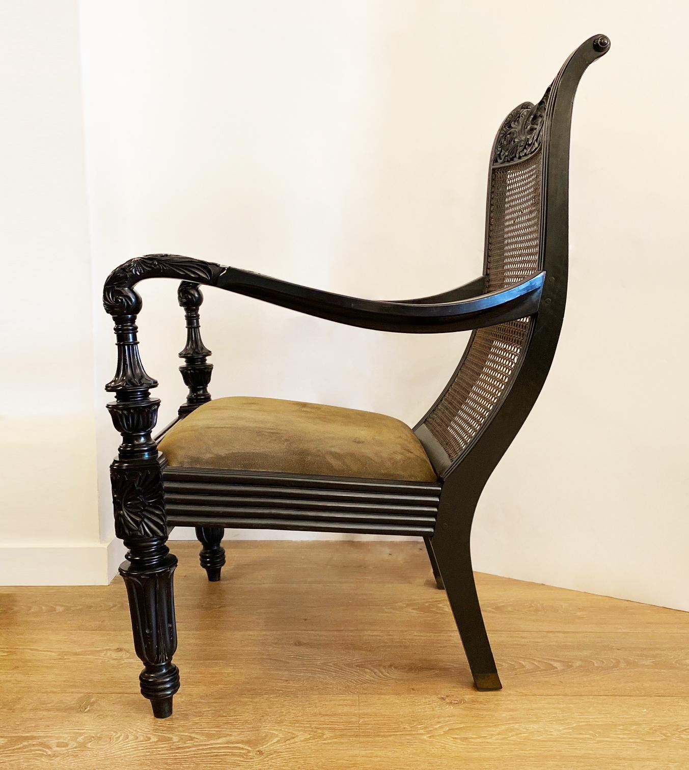 Rare pair of 19th century Anglo-Indian lounge chairs
Solid hand-carved ebony armchairs, curved back, long arms and raised on turned front legs. 
Caned back and original suede upholstered seats
Ceylon, Galle District, circa 1840
A similar chair