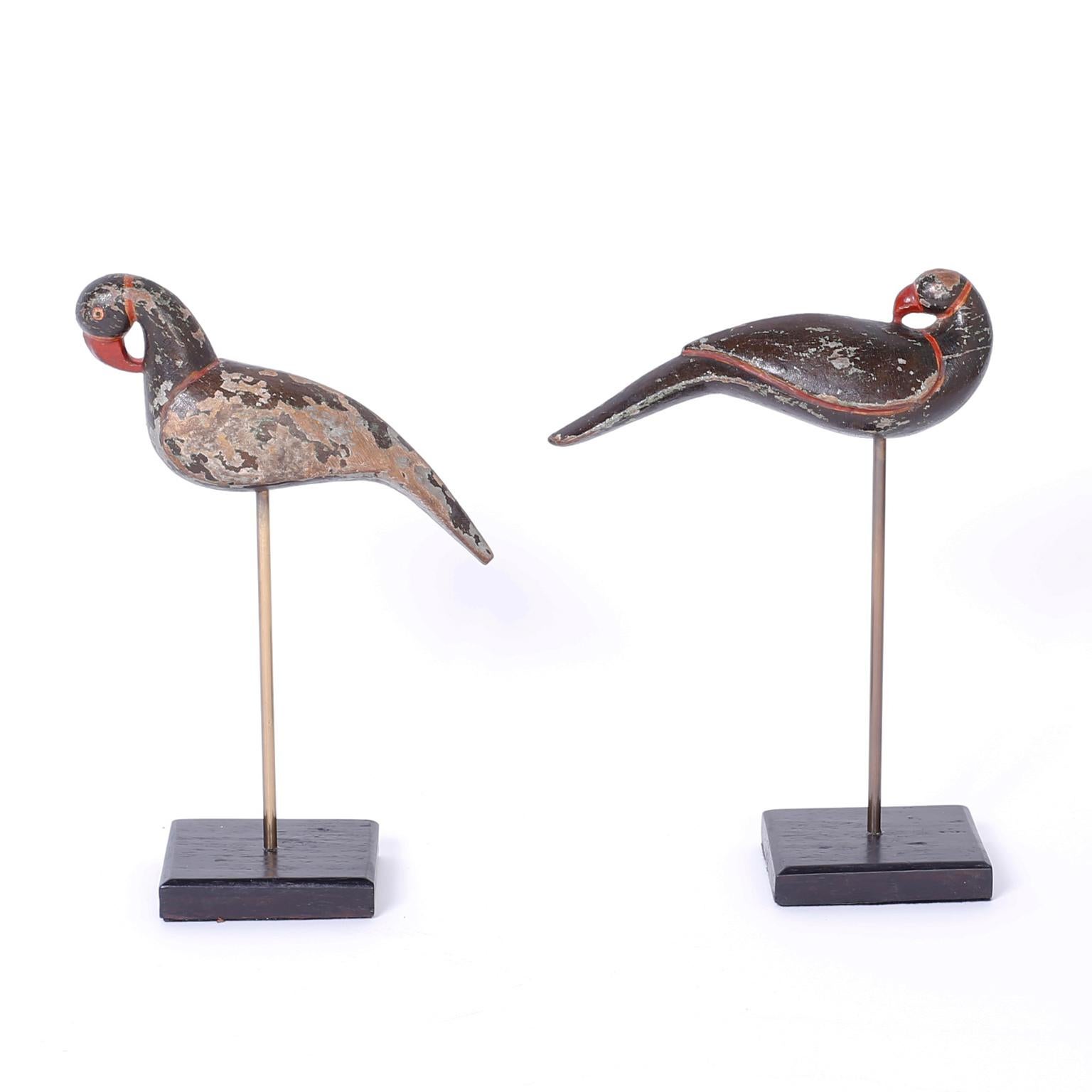 Amusing pair of antique anglo Indian birds with a folky charm that have been carved from indigenous hardwood and painted a long ago, now with a rustic patina. Presented on custom stands.