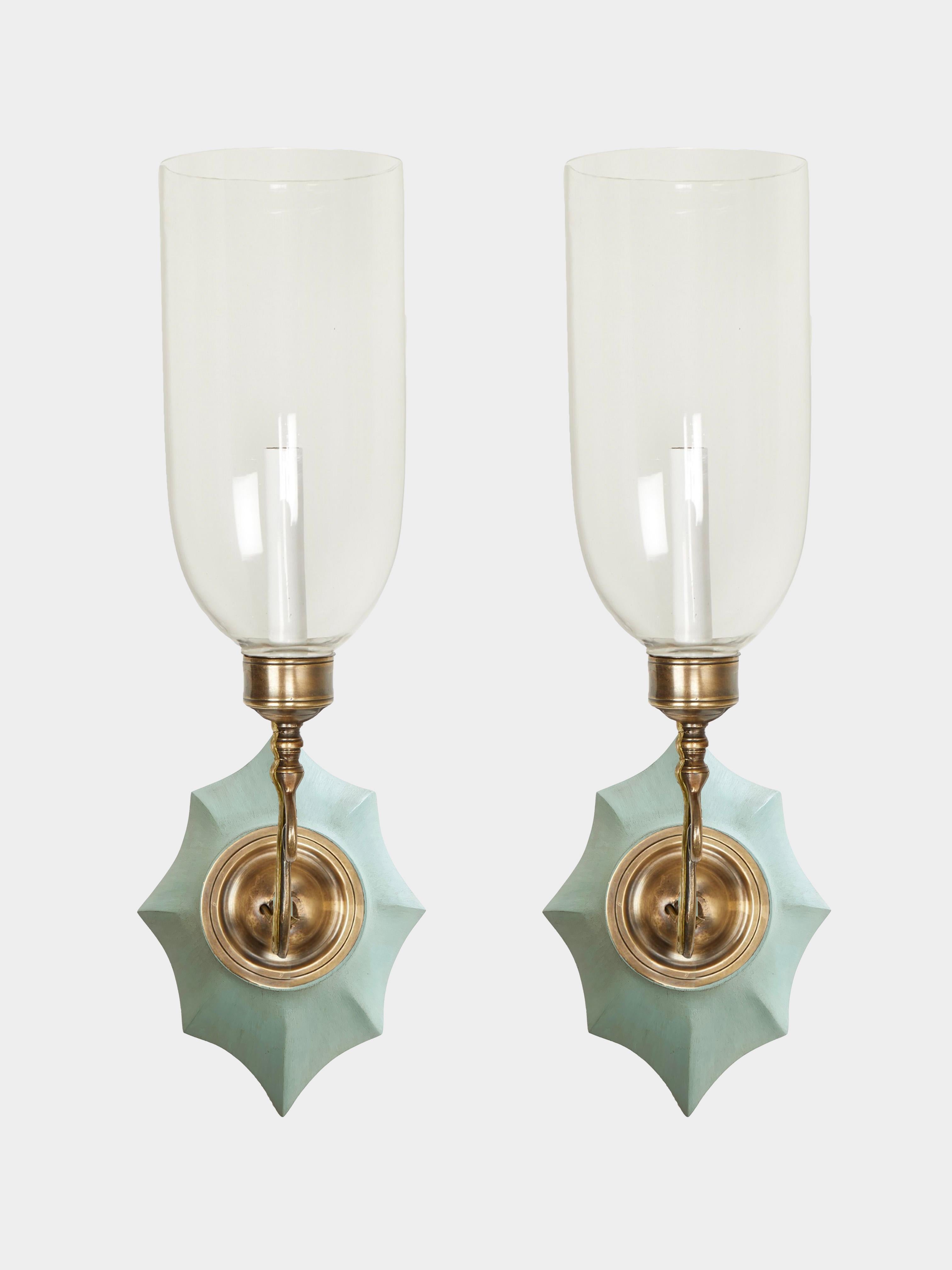 A pair of hand-carved mahogany Boissy backplates with patinated brass sconce fittings and clear glass hurricane shades. Electrified with one candelabra base socket per sconce.

Our custom hurricane sconces are available with wood, painted or gilt