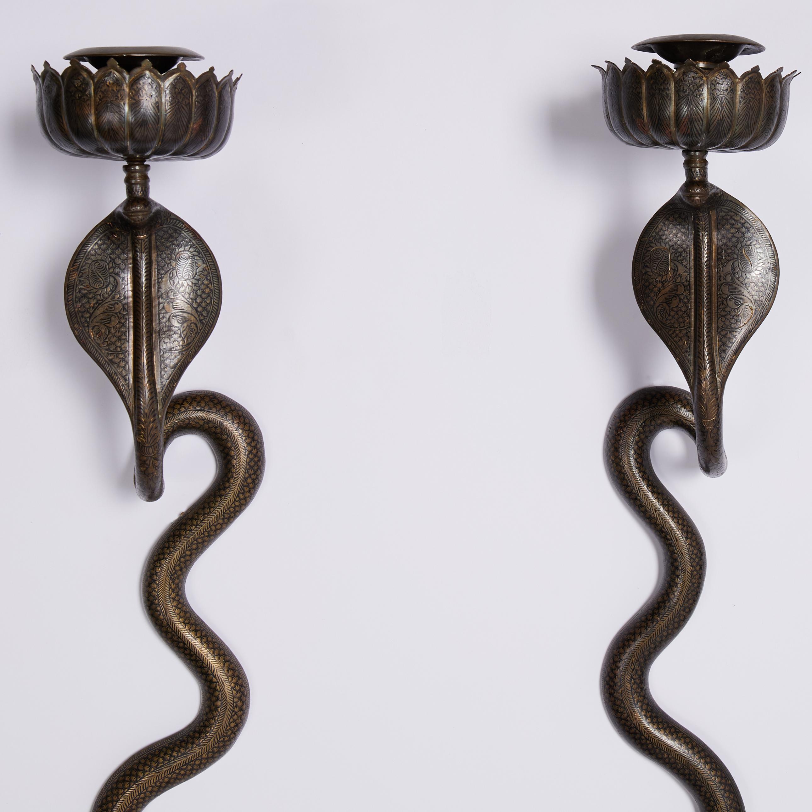 Standout pair of vintage Anglo Indian cobra or snake wall sconces crafted in brass with etched floral and geometric designs highlighted in black enamel and having an overall bronze like patina.