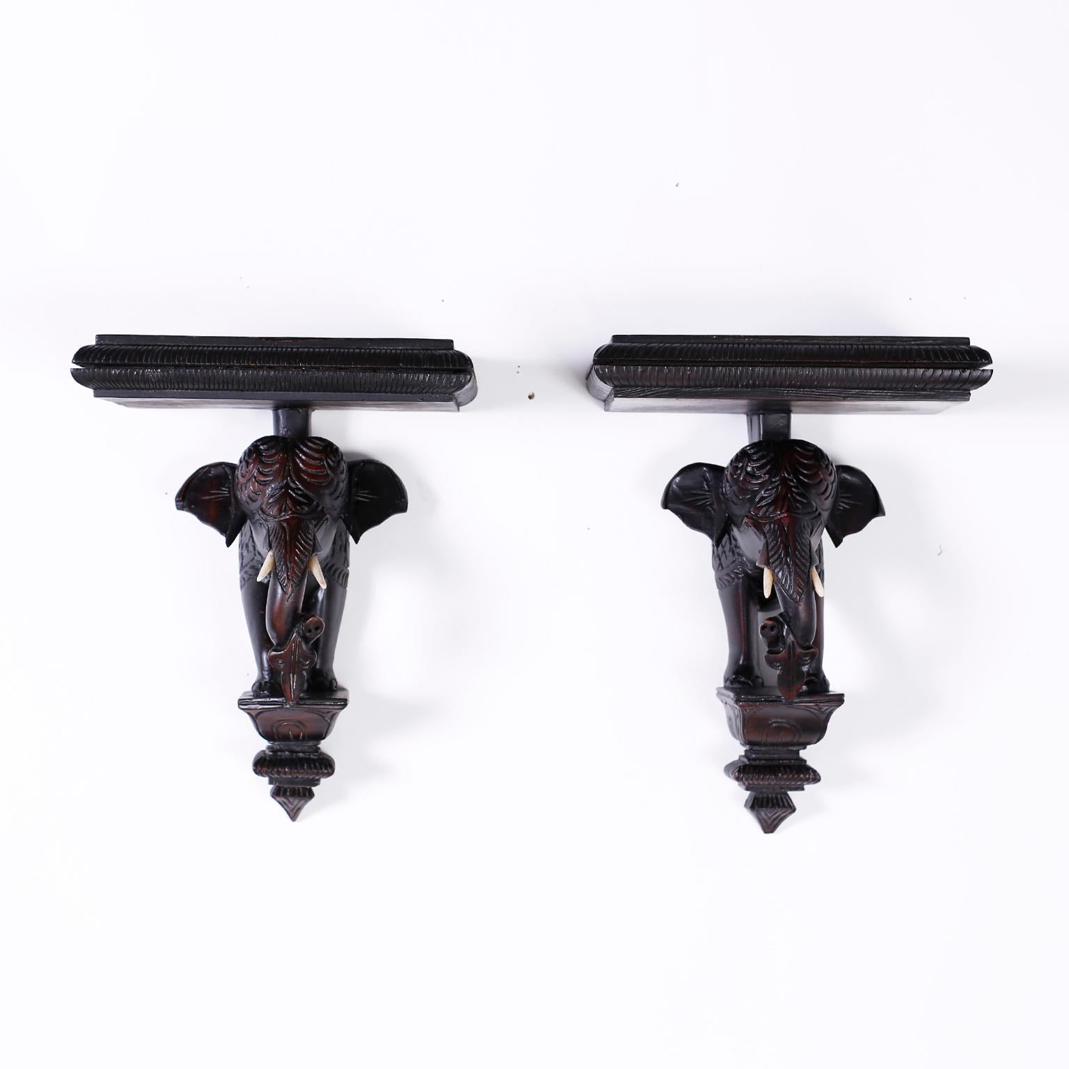 British colonial style Anglo Indian wall brackets crafted in mahogany, depicting elephant busts on pedestals supporting a shelf with an ebonized finish.