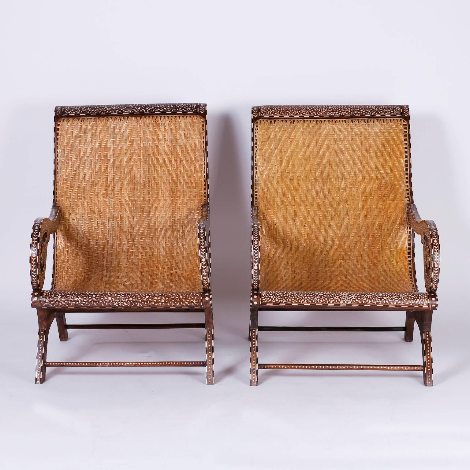 Pair of dashing hand caned Anglo-Indian plantation chairs crafted in rosewood with a dramatic form and decorated with inlaid bone and ebony. Perfect for West Indies and British Colonial interior.