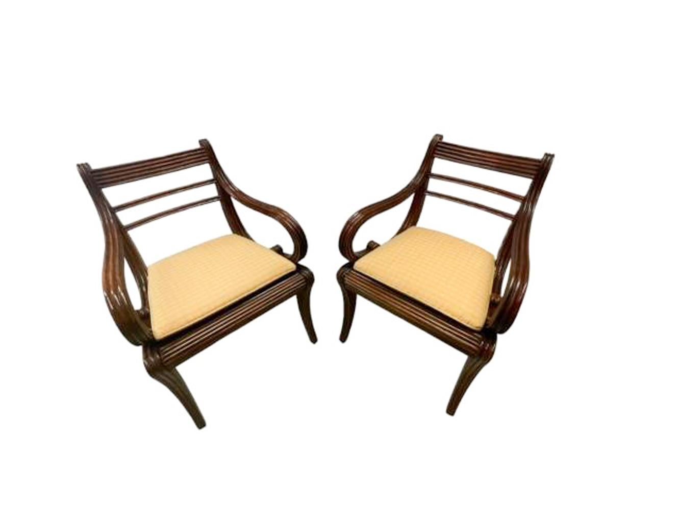 Fine pair of Anglo-Indian carved mahogany armchairs in the English Regency taste. Front and side surfaces carved with reeded surfaces, the back curving back at the crest rail with exaggerated curling arms and hand-woven cane seat supported on saber