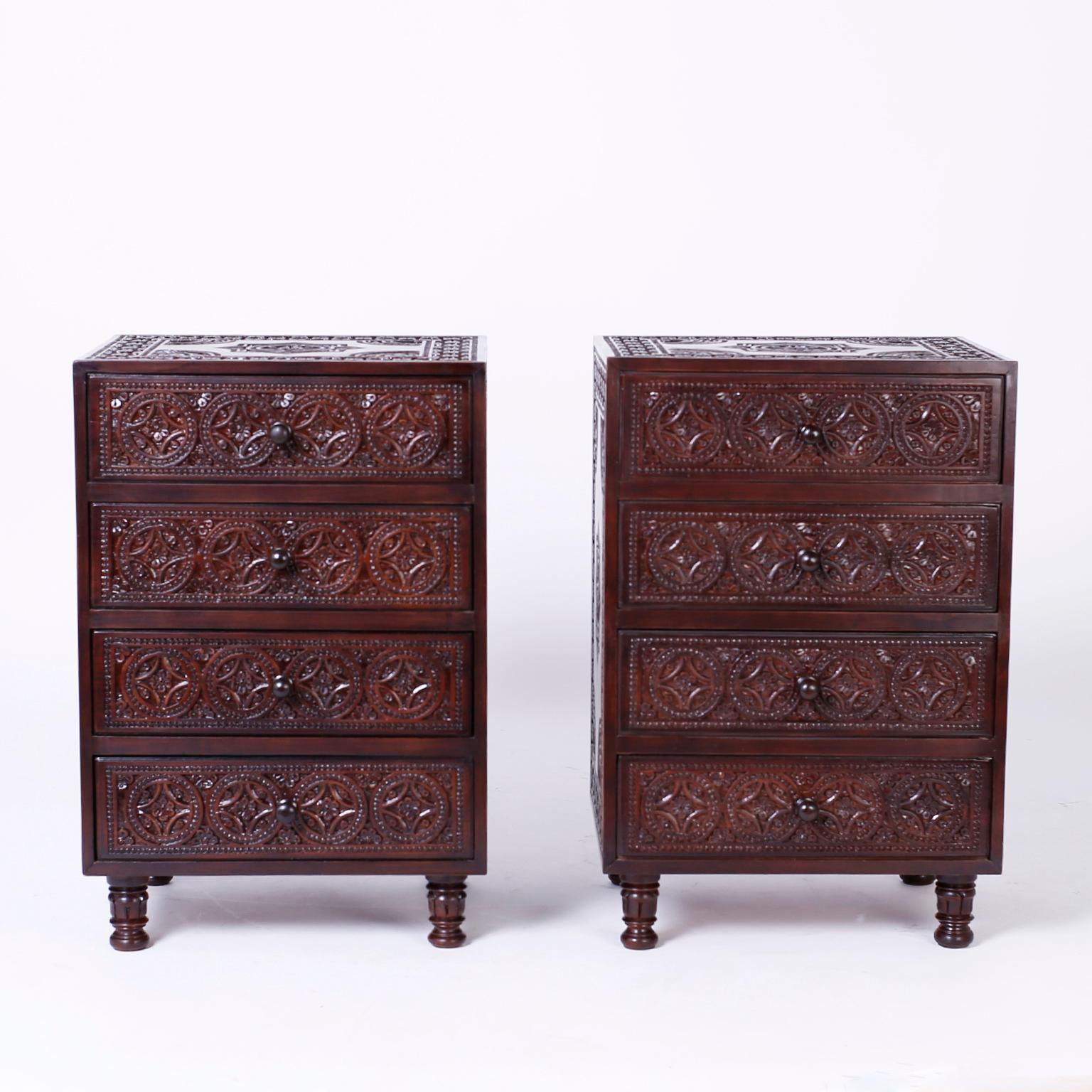 Pair of exotic Anglo-Indian four drawer mahogany nightstands or chests expertly carved on the top, sides and front with floral designs and medallions and set on carved and turned feet.