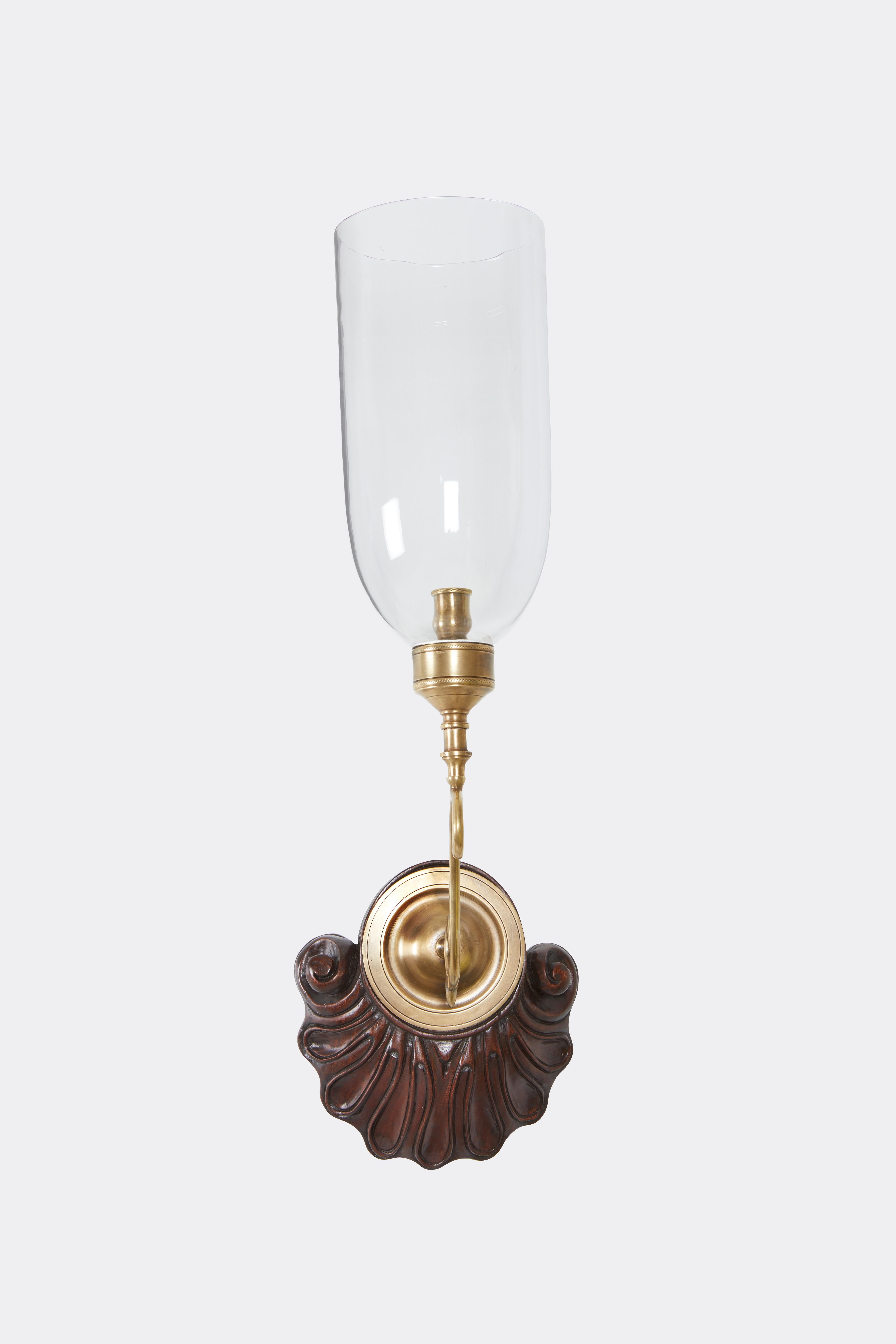 A pair of Georgian-style sconces with cast brass arms, glass hurricane shades, and hand carved mahogany backplates. 

Our custom hurricane sconces are available with wood, painted or gilt finishes. The backplates can be fitted with brass or nickel