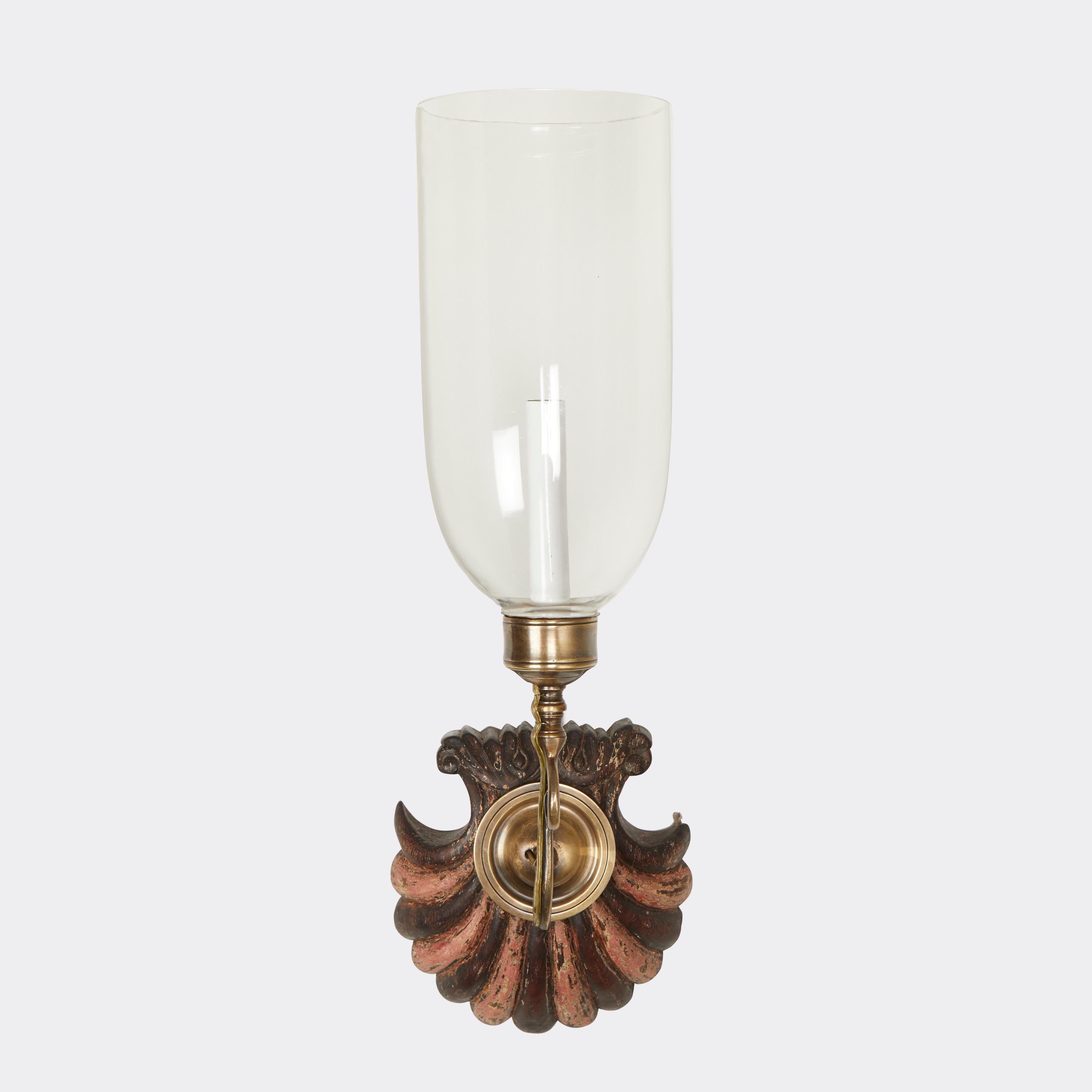 A pair of antique hand-carved scalloped shells from mahogany Anglo Indian backplates with painted decoration with pink stripes alternating with mahogany, patinated brass sconce fittings, and hand-blown clear glass. Electrified with one
